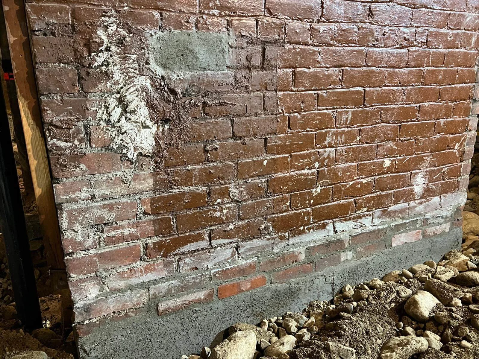 New concrete at the base, original brick repaired above. Old and new, built to work together.