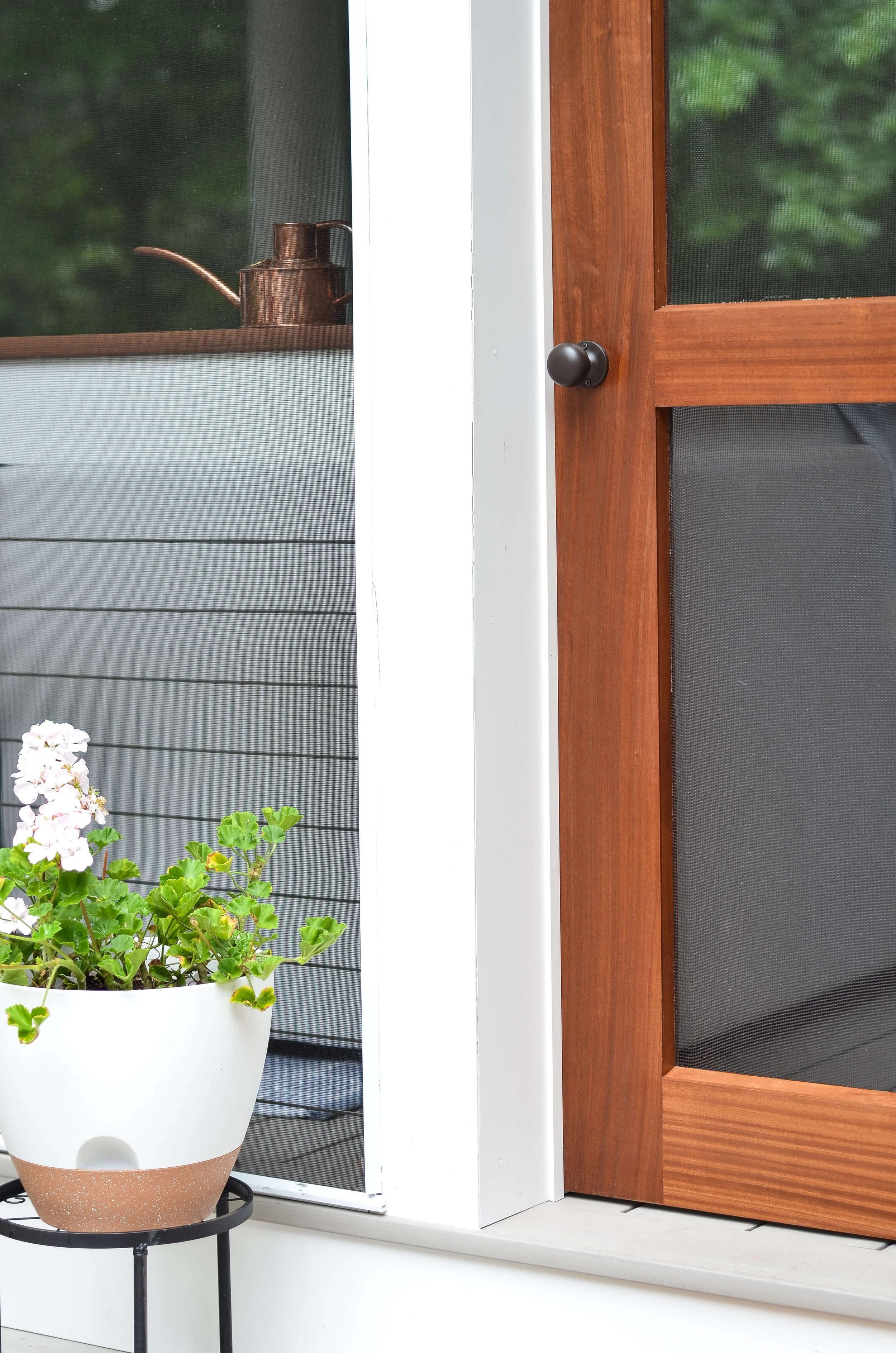 Where the screen door meets the trim: warm wood grain, crisp white edges.