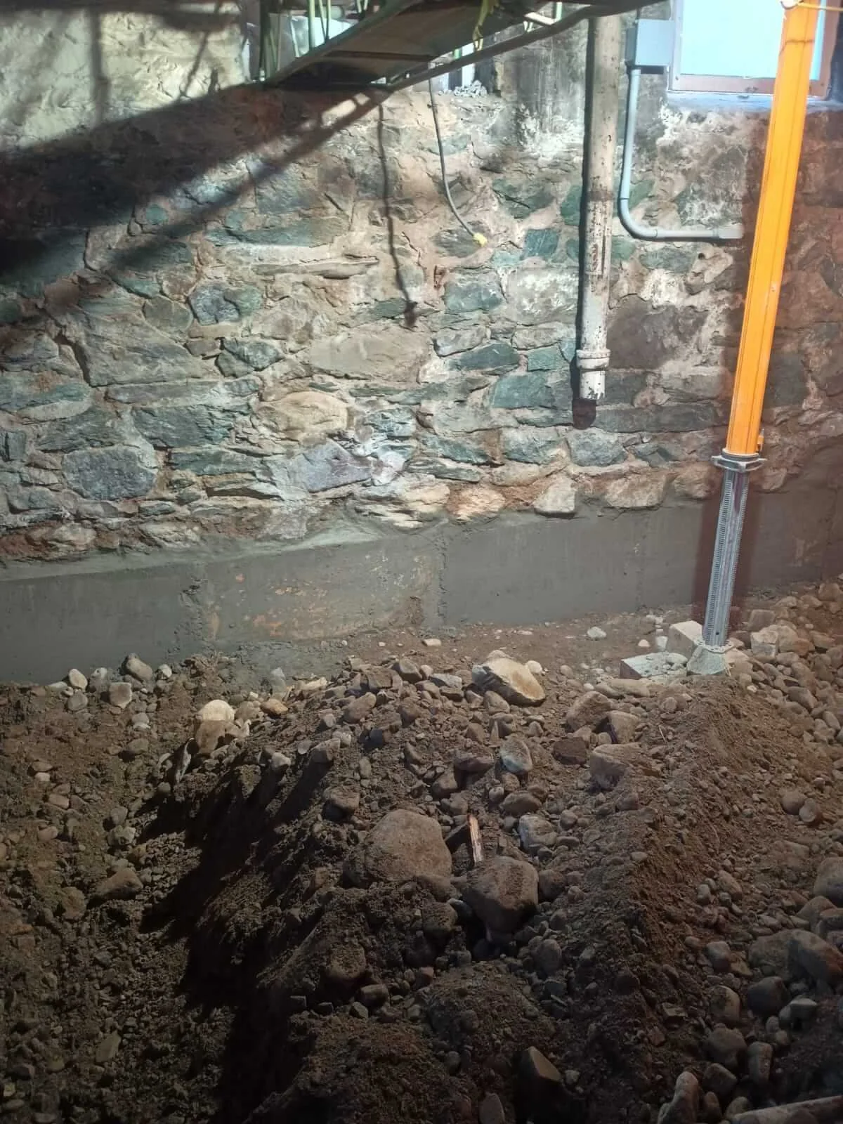Original stone above, new concrete below. The old foundation stays, now on stronger footing.