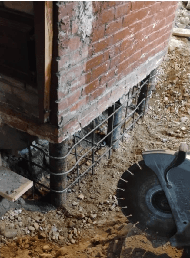 Brick above, rebar below. The new foundation takes shape directly under the original wall.