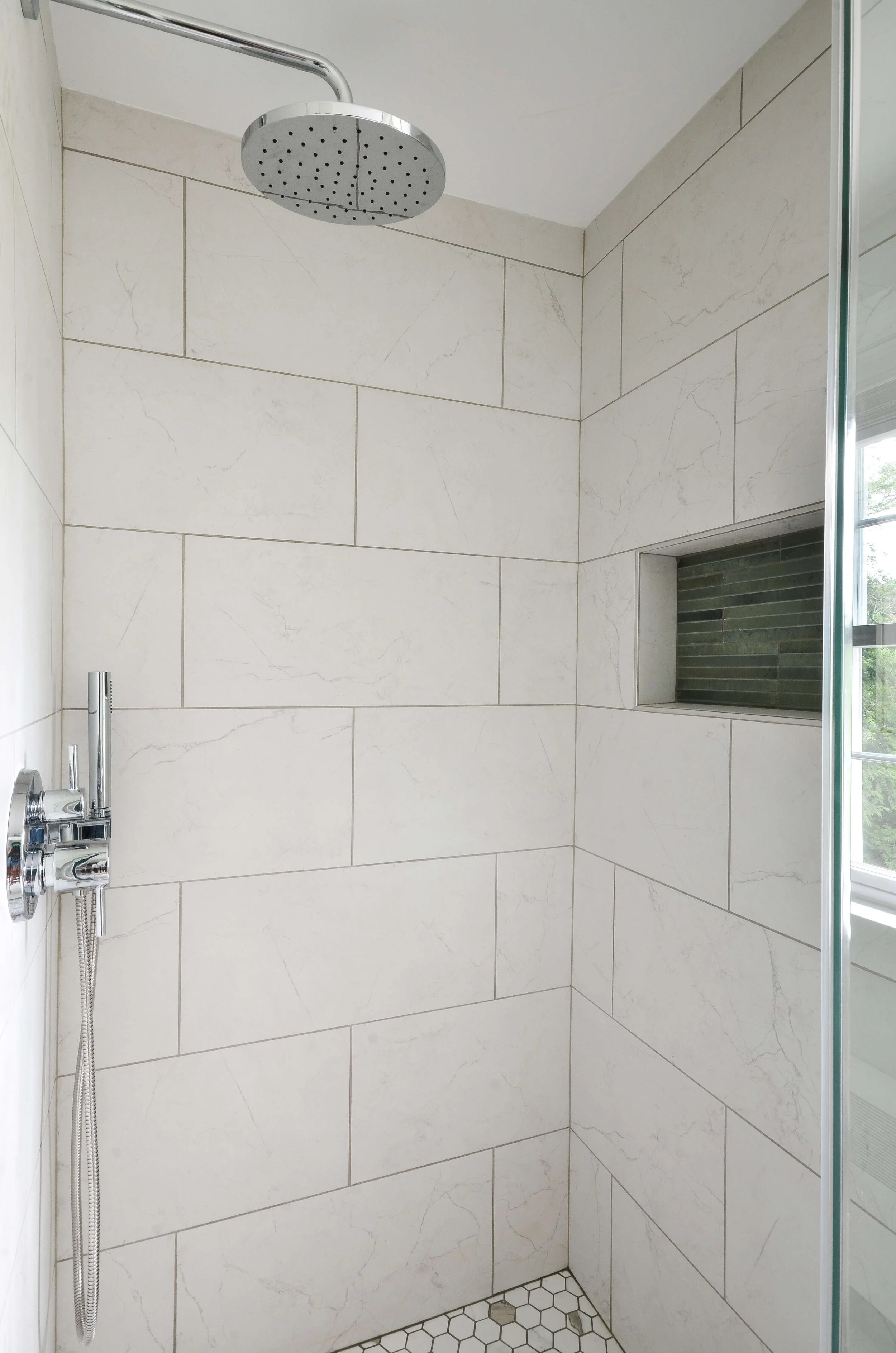 A rain shower head off the vertical wall, paired with a built-in niche. Bright, airy, and detailed throughout.