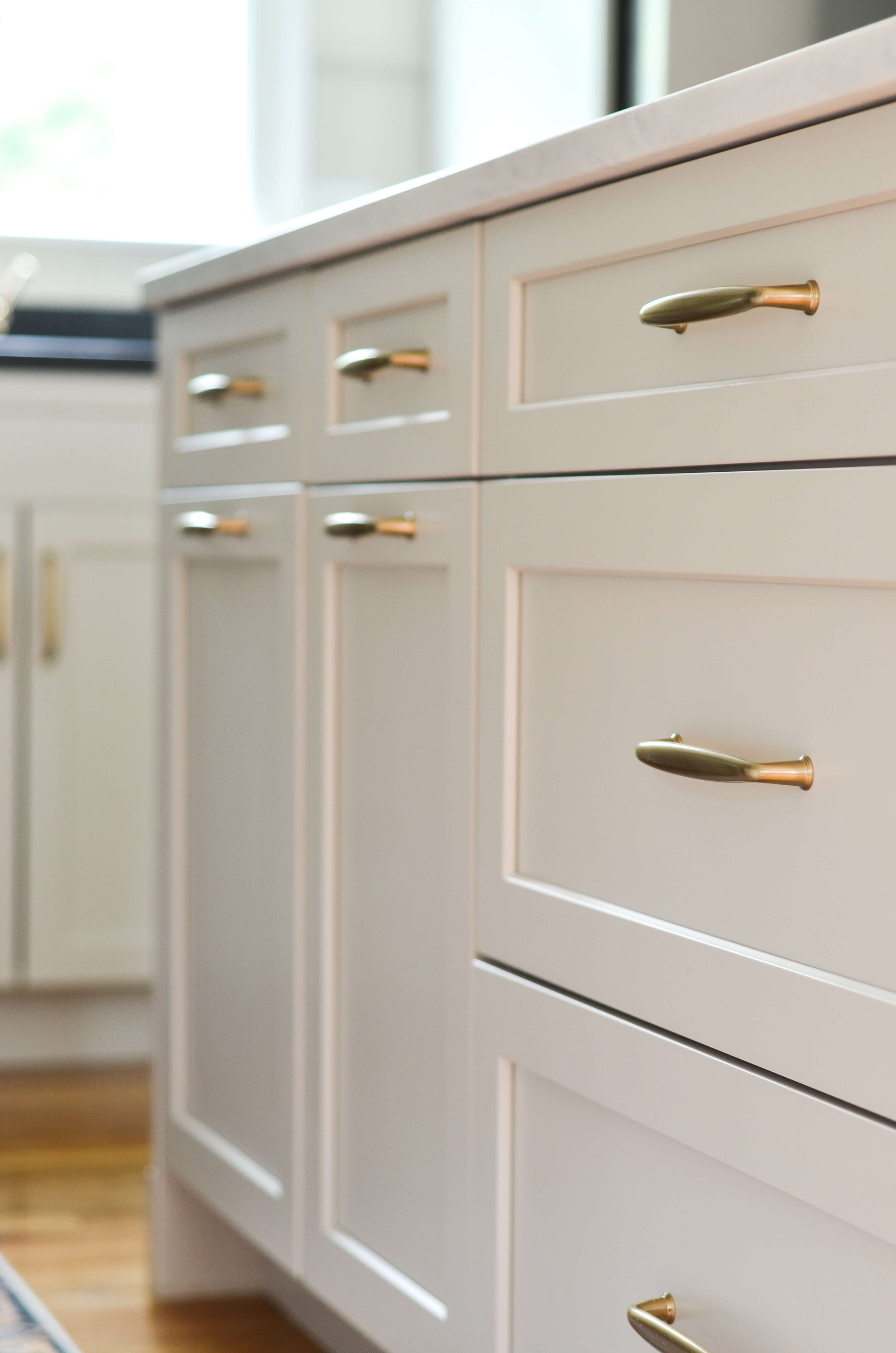 Brass hardware, echoed in the floor's warm tone. A small detail that ties the whole space together.