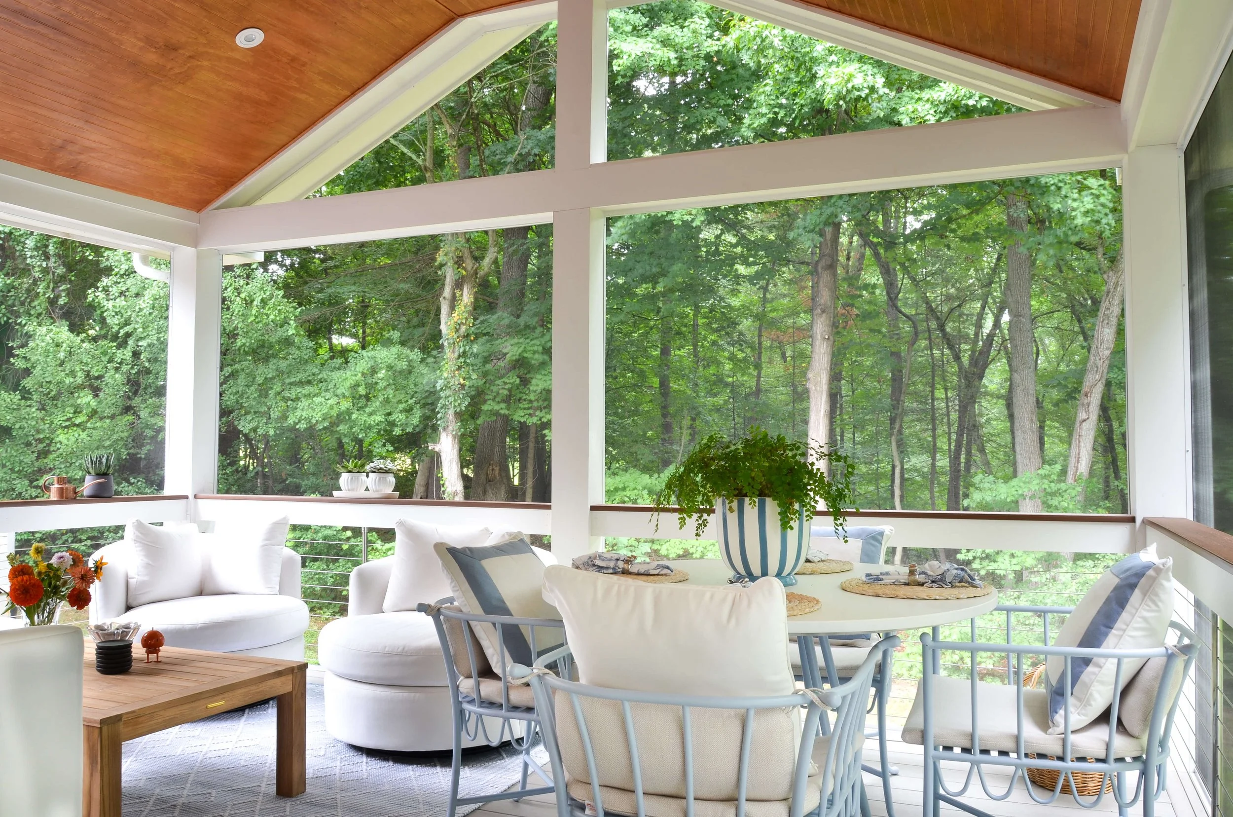 Lounge and dining under one gable, with the woods as the backdrop.