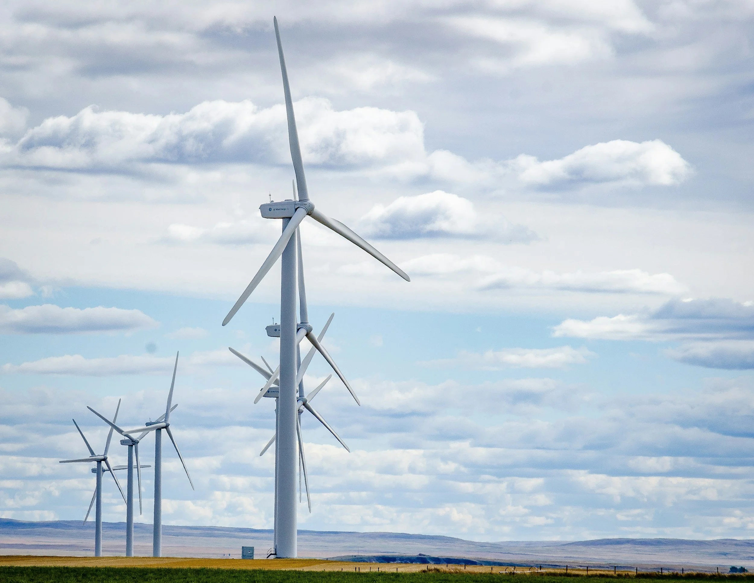 Une rangée d'éoliennes dans un paysage plat avec un ciel nuageux.