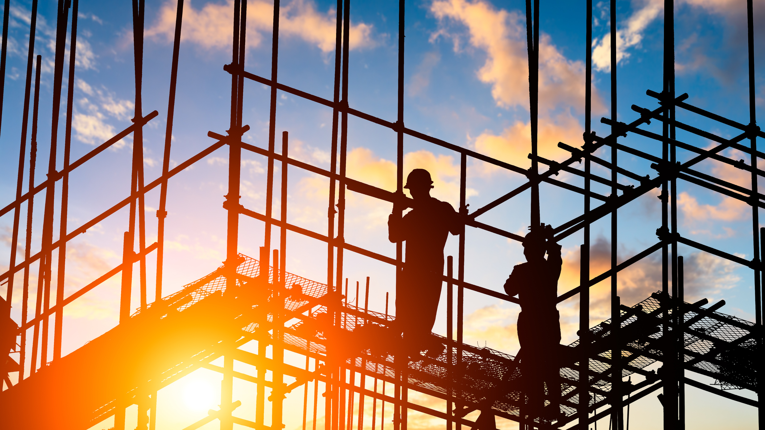 Silhouettes de travailleurs du bâtiment sur un échafaudage au coucher du soleil, ciel avec nuages