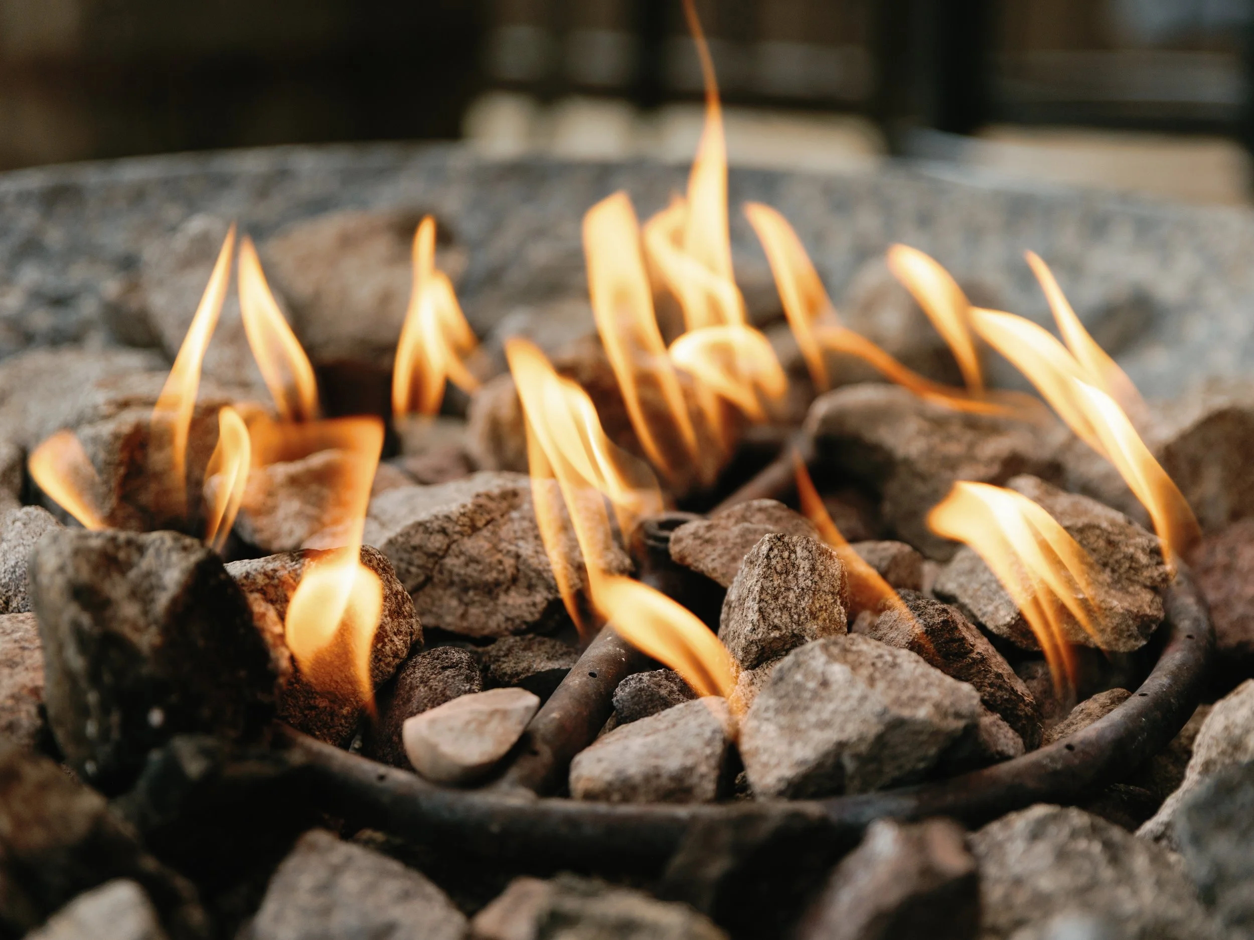 Close-up of a fire pit with flames and rocks around it.