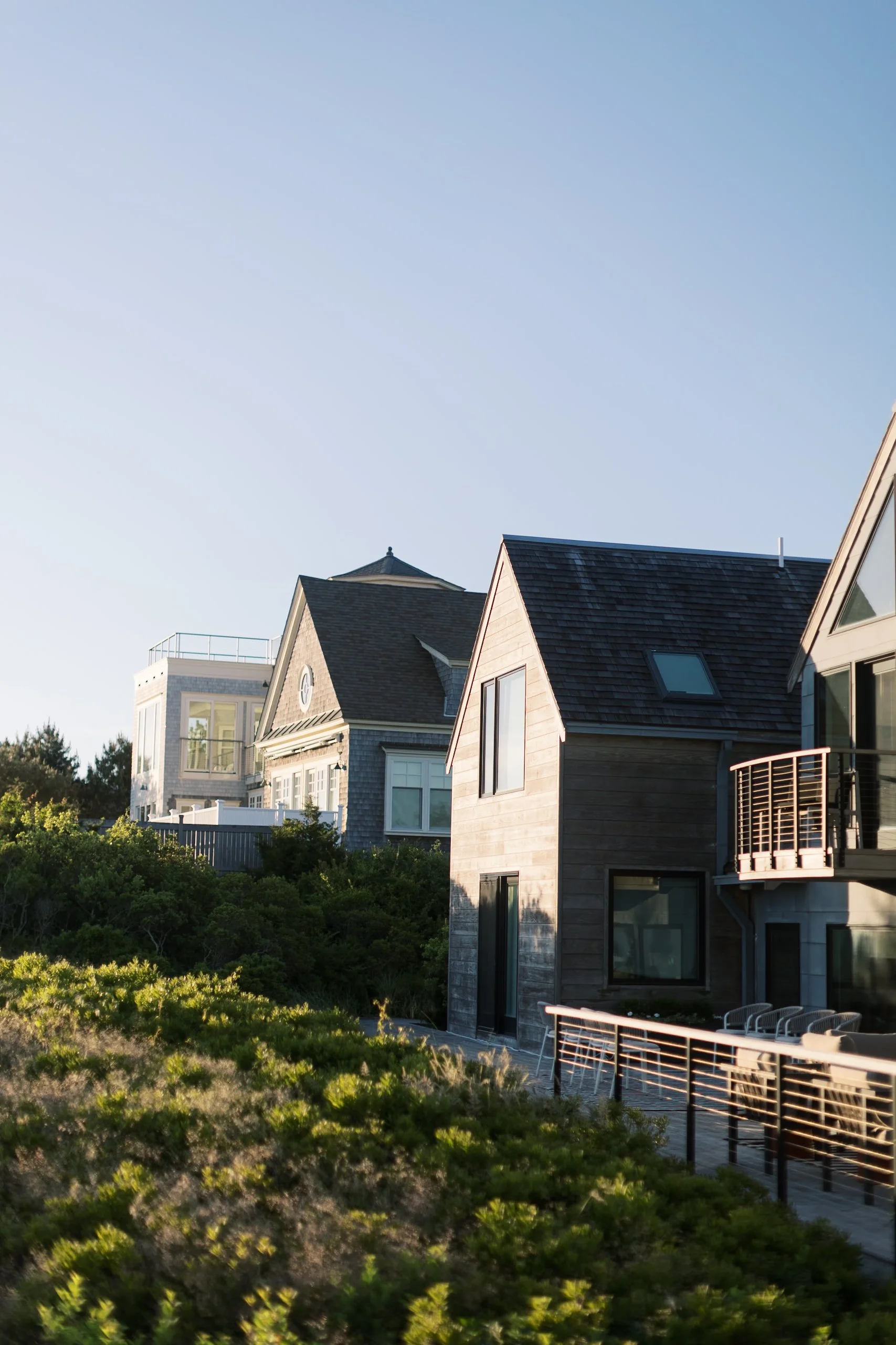 A row of modern houses on a hillside with clear blue sky in the background.