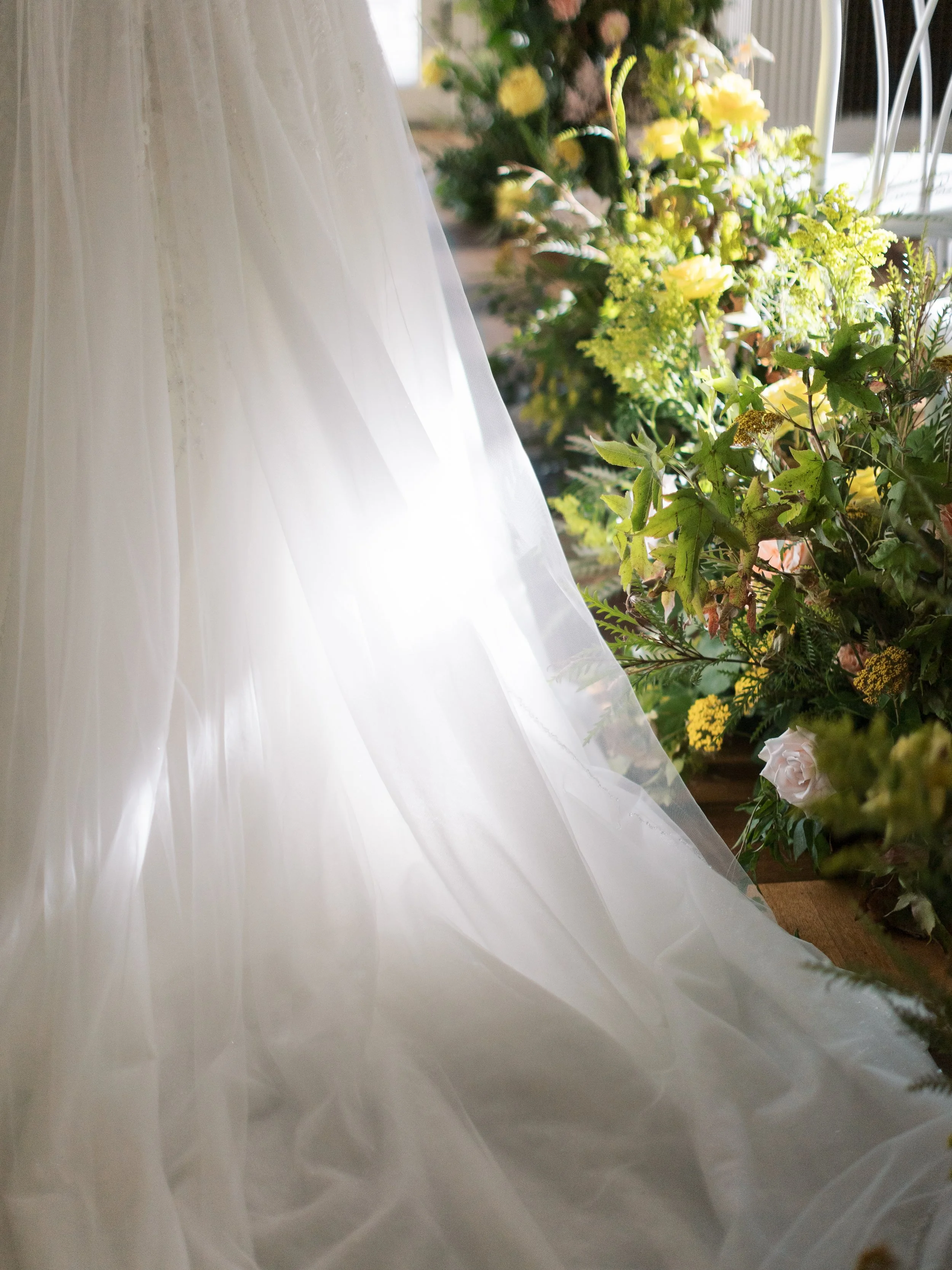 Part of a wedding dress and bouquet of flowers on a table