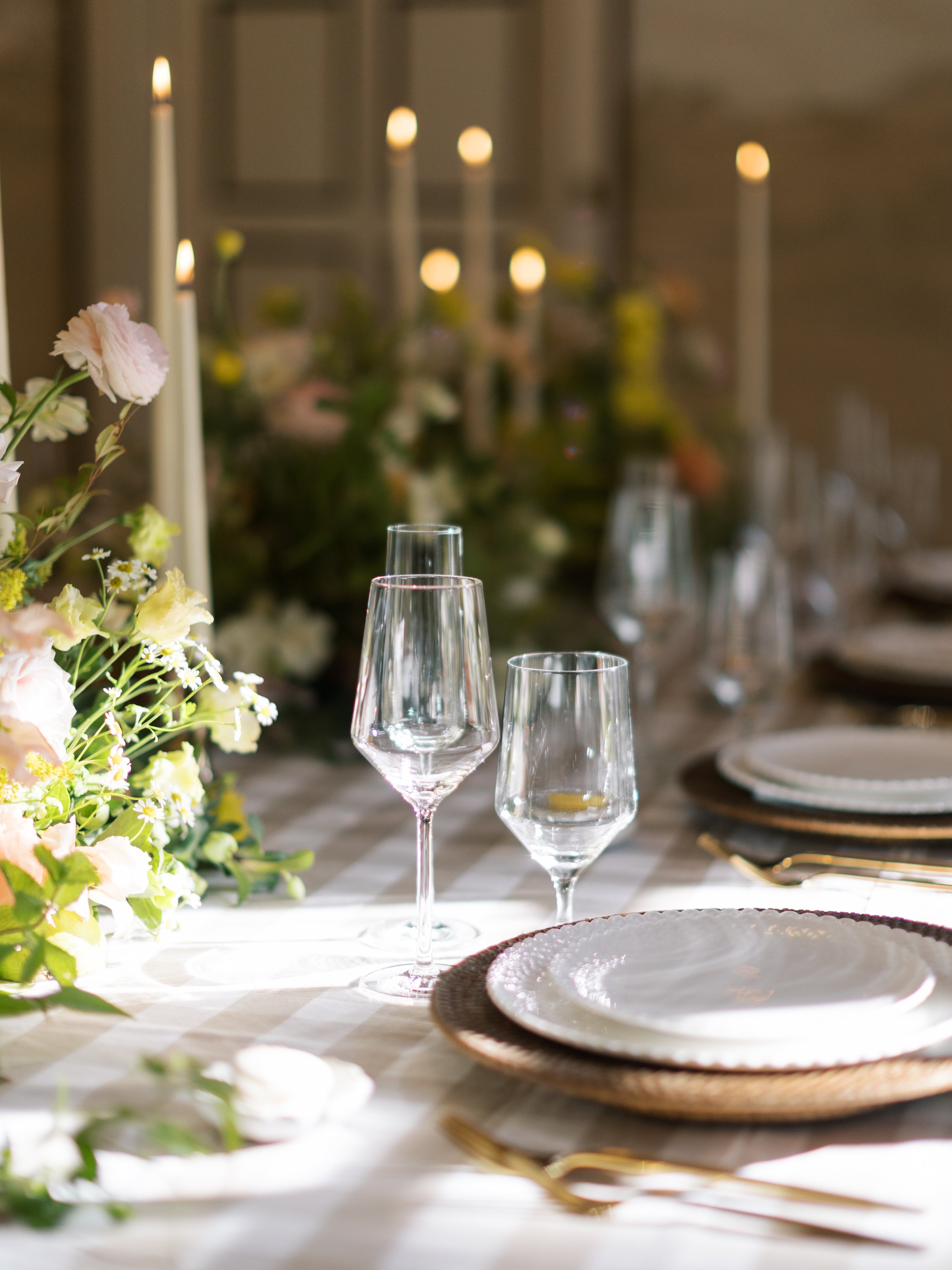 Elegant dining table set with floral centerpiece, wine glasses, and lit candles, prepared for a special occasion.
