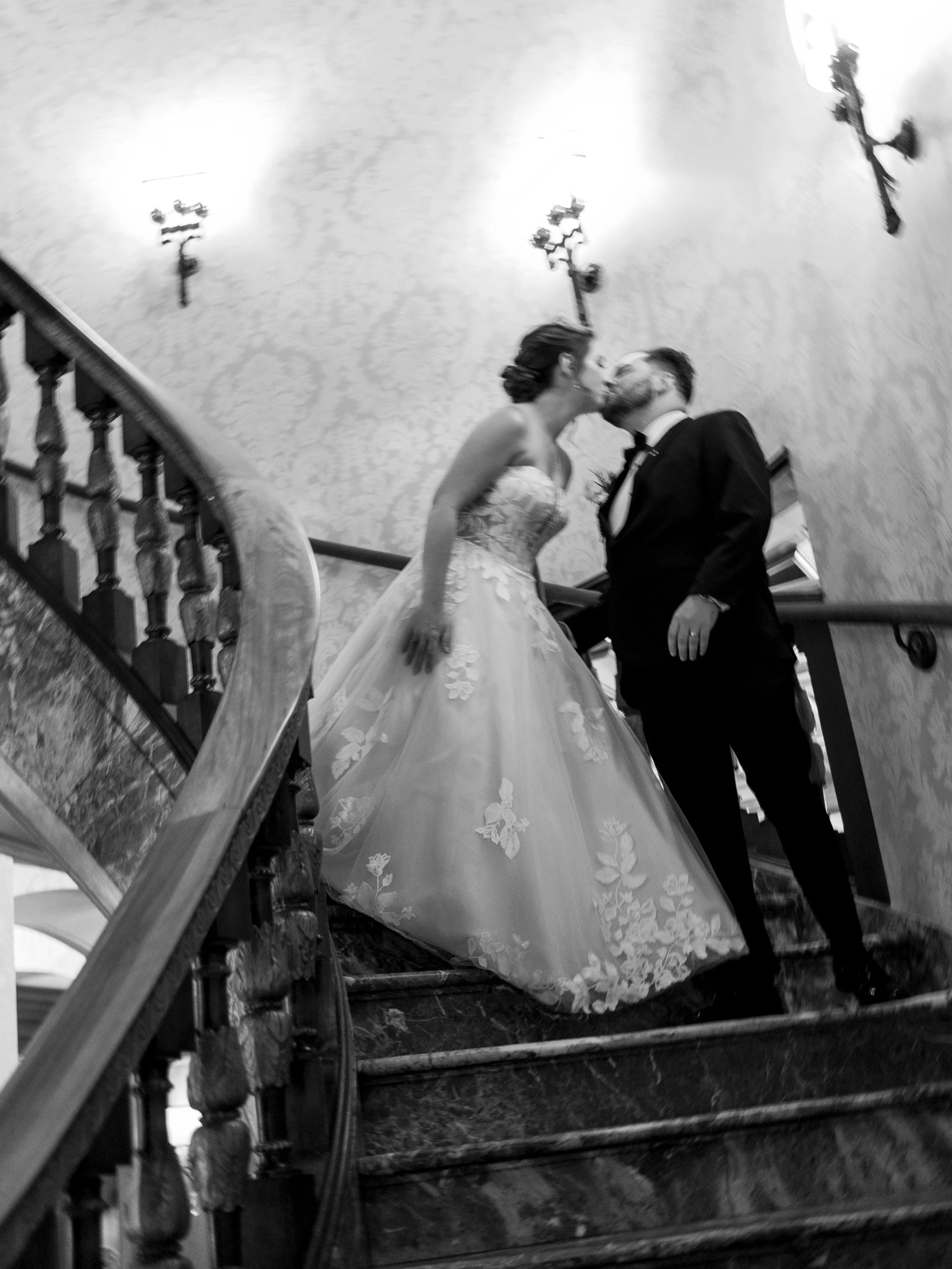 A bride and groom kissing on a staircase at their wedding.