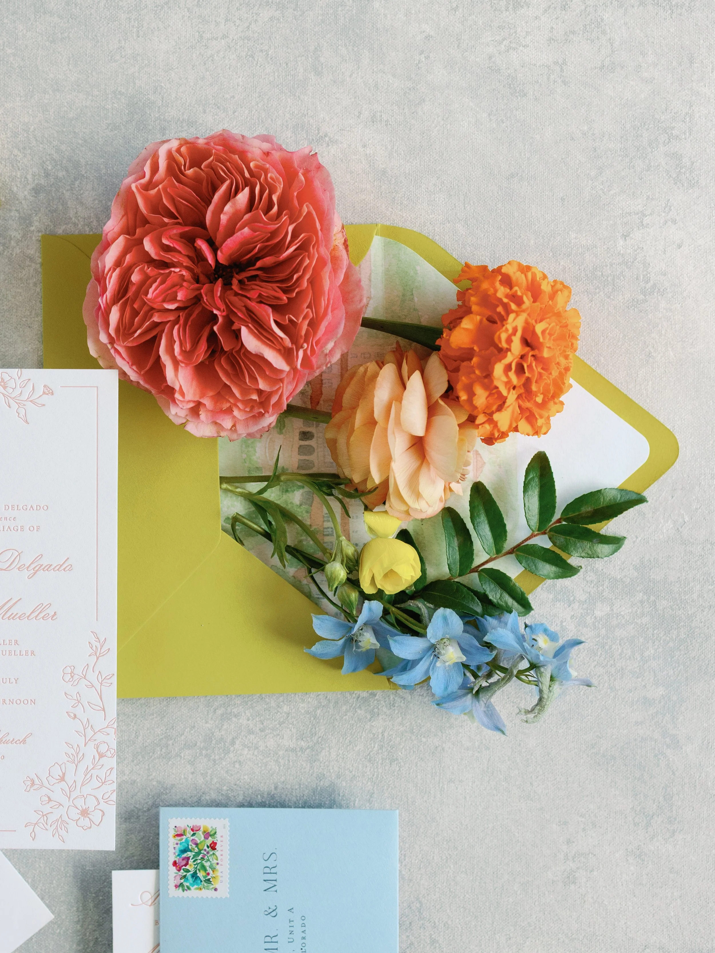 A bouquet of colorful flowers including pink, orange, yellow, and blue blooms on a table, possibly part of a wedding or special occasion setup.