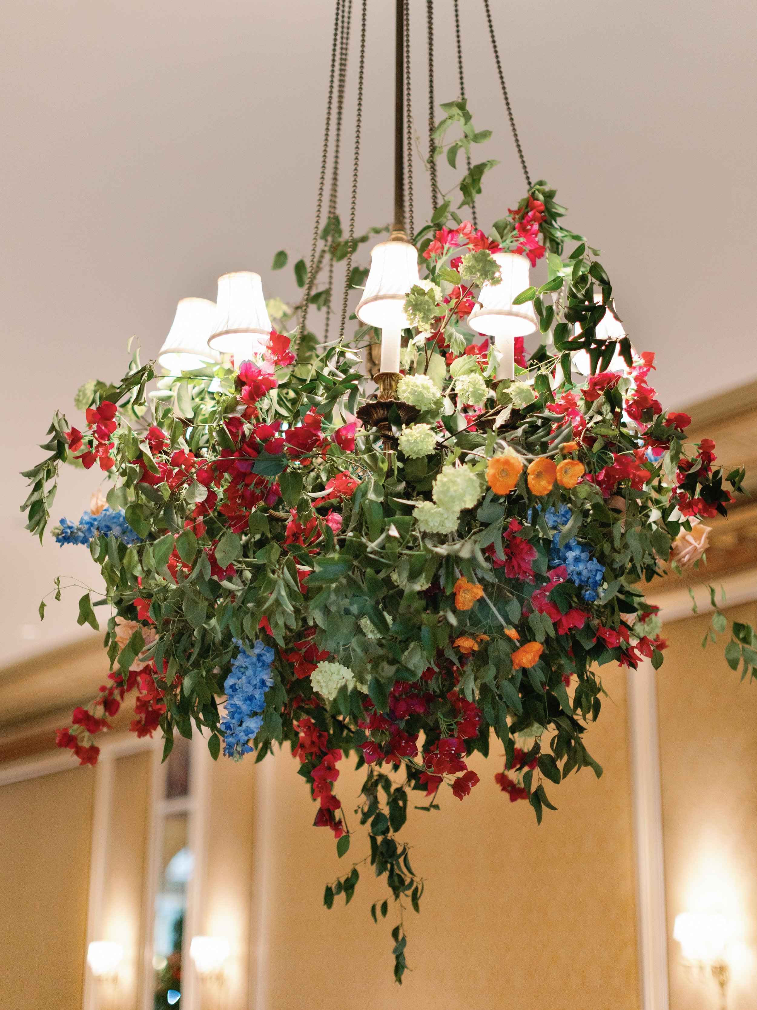 A floral chandelier with colorful flowers and hanging lamps, suspended from the ceiling indoors.