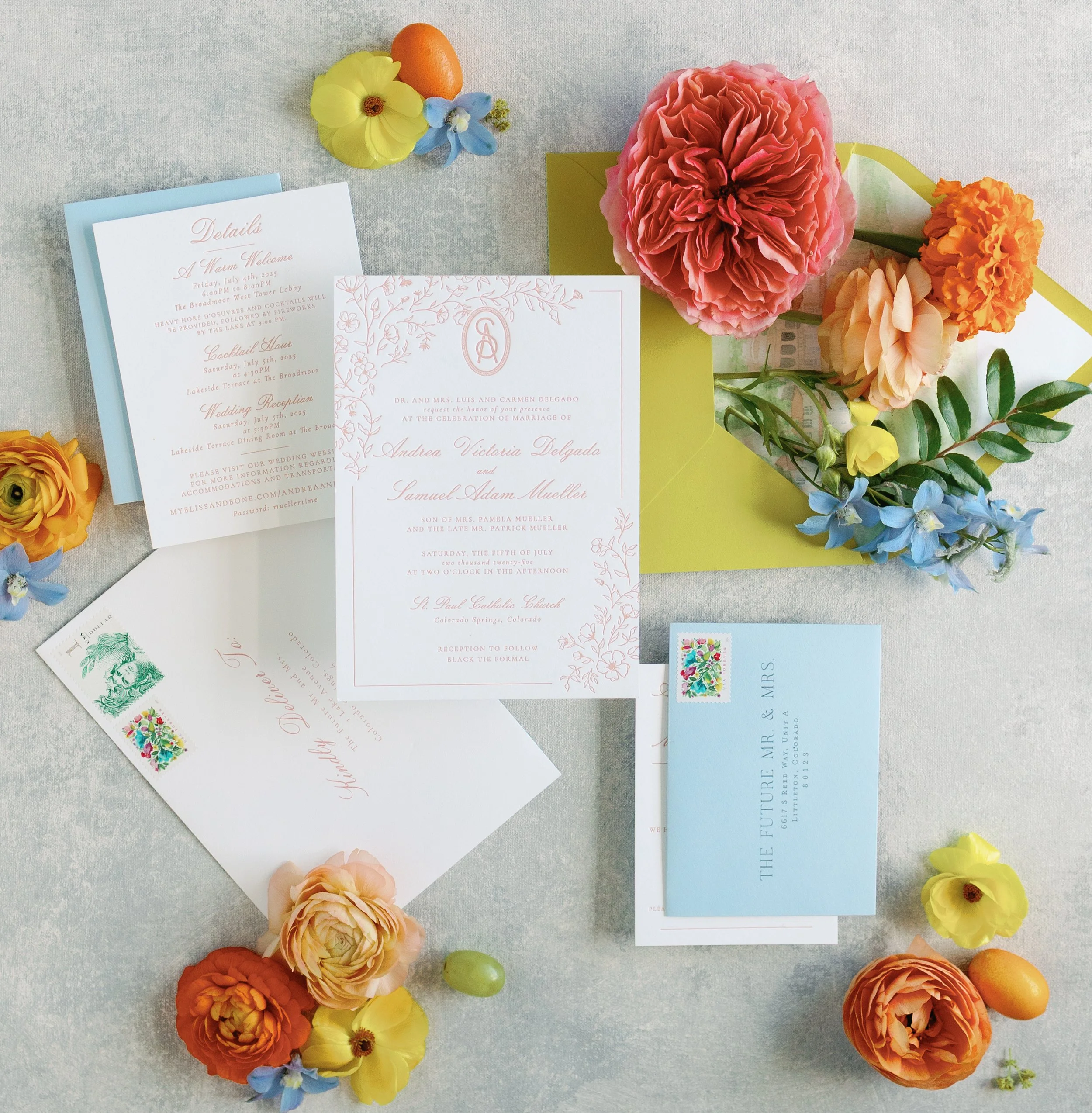 Wedding invitation cards, RSVP card, and envelope with colorful flowers and small fruits on a light-colored surface.