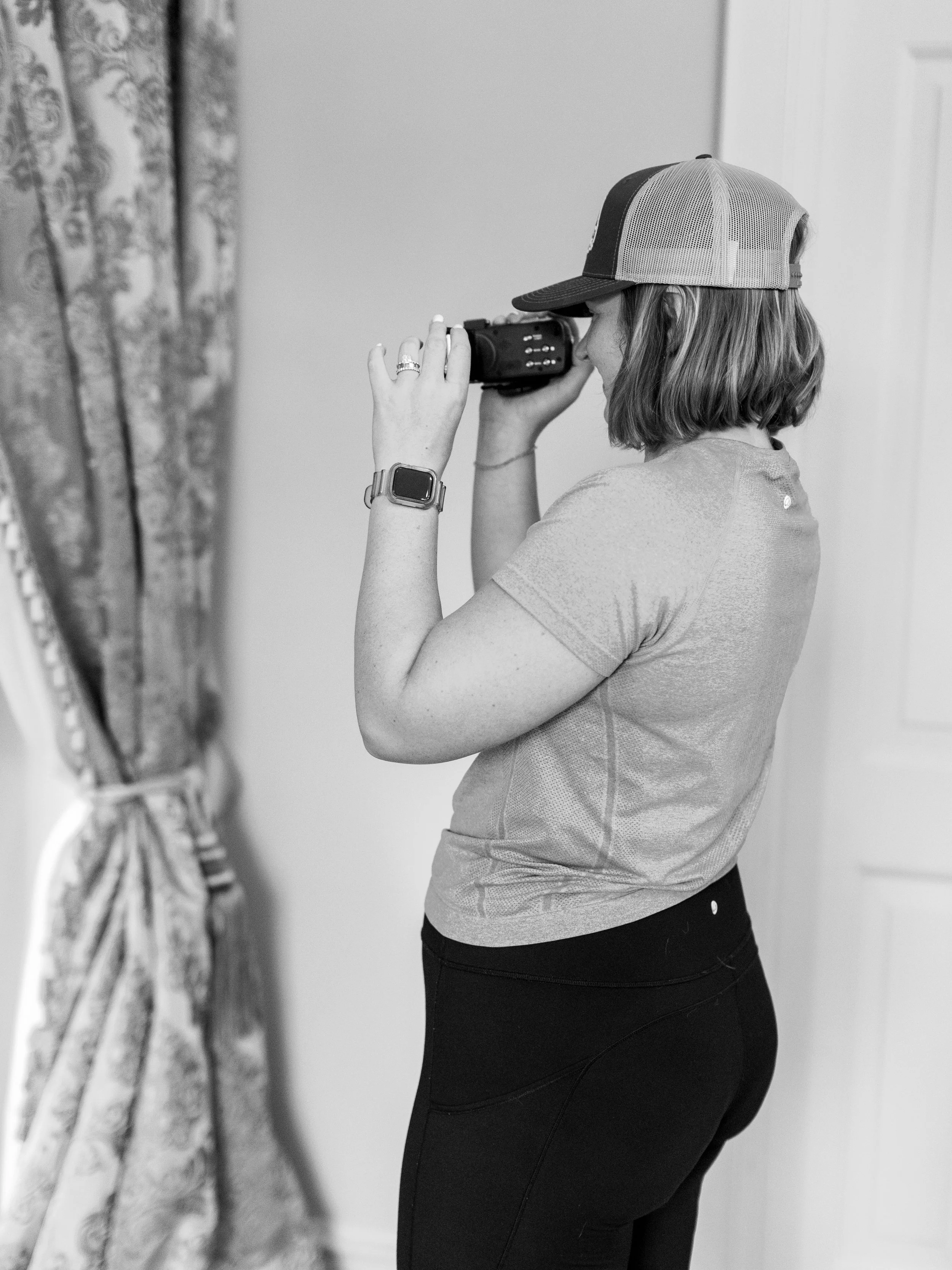 A woman with a cap, watching through binoculars in a room