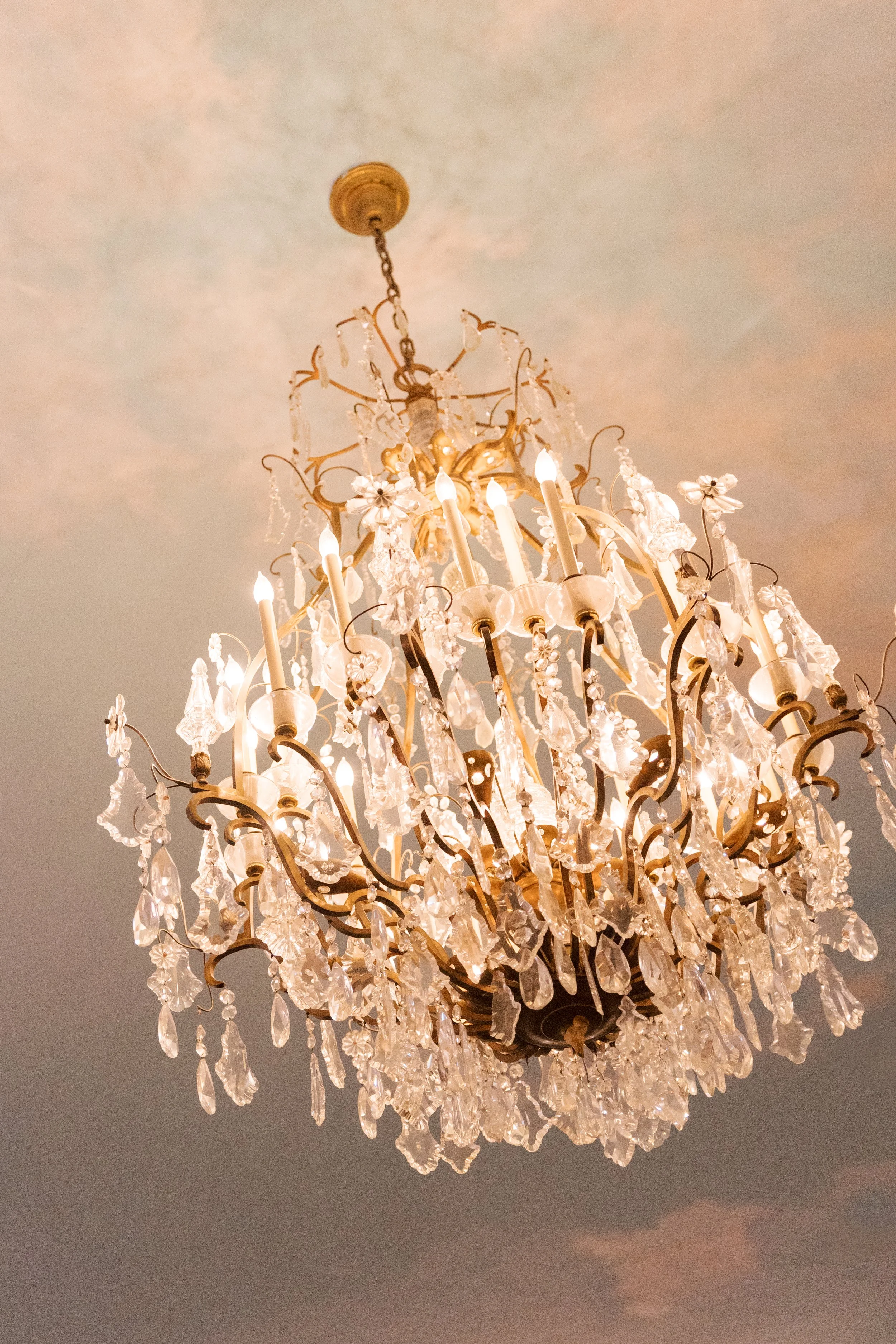 A crystal chandelier with lit candles hanging from a ceiling.