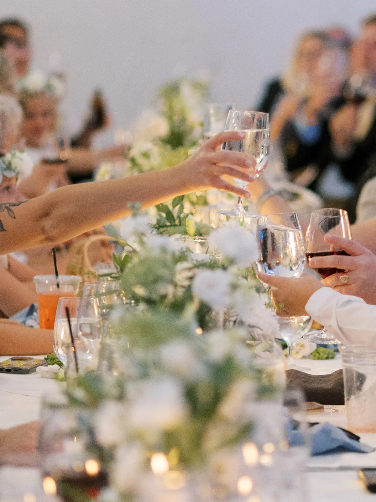 Guests raising glasses in toast at a formal dinner party.