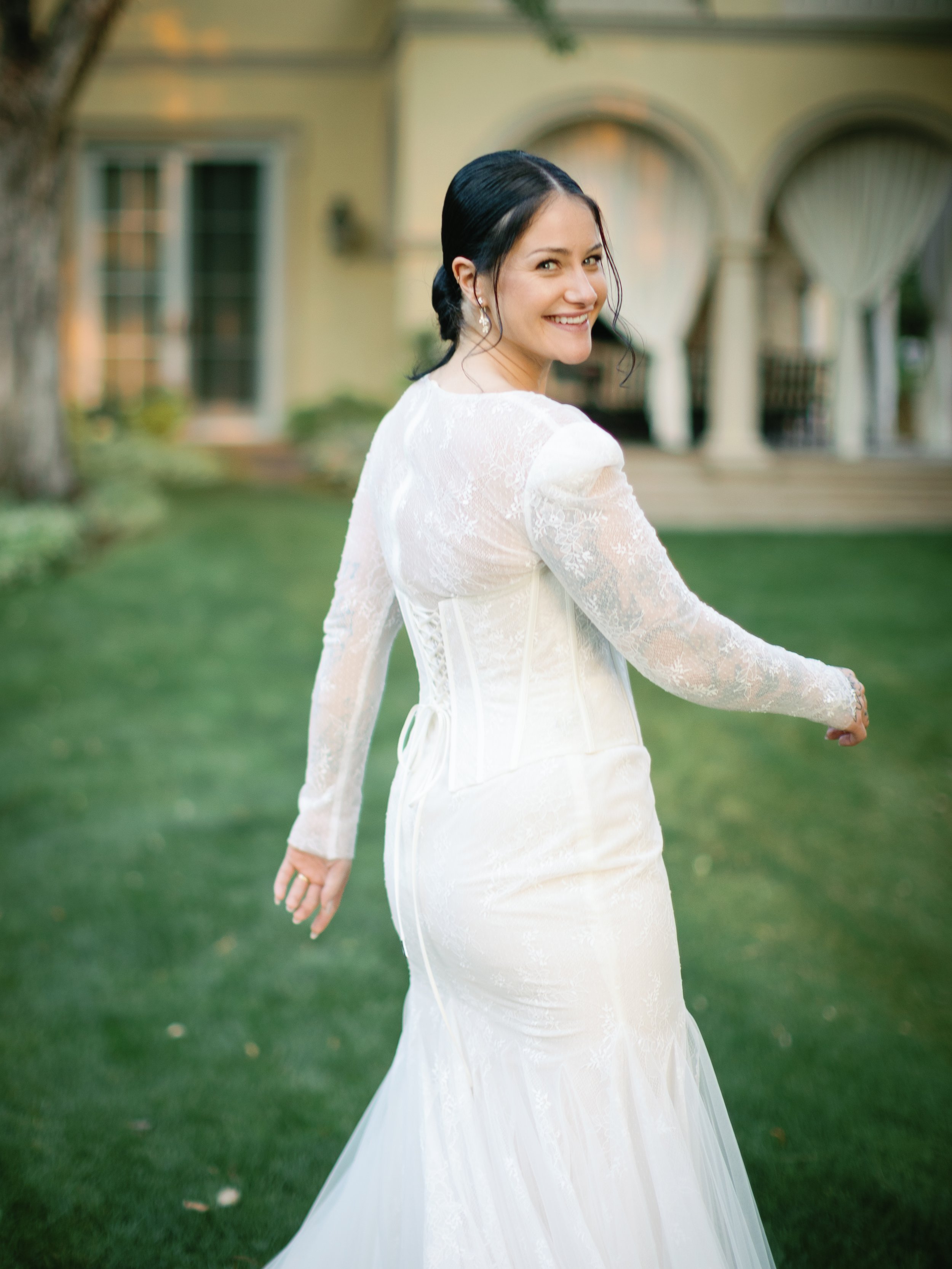Woman in wedding dress smiling while walking on grass outside