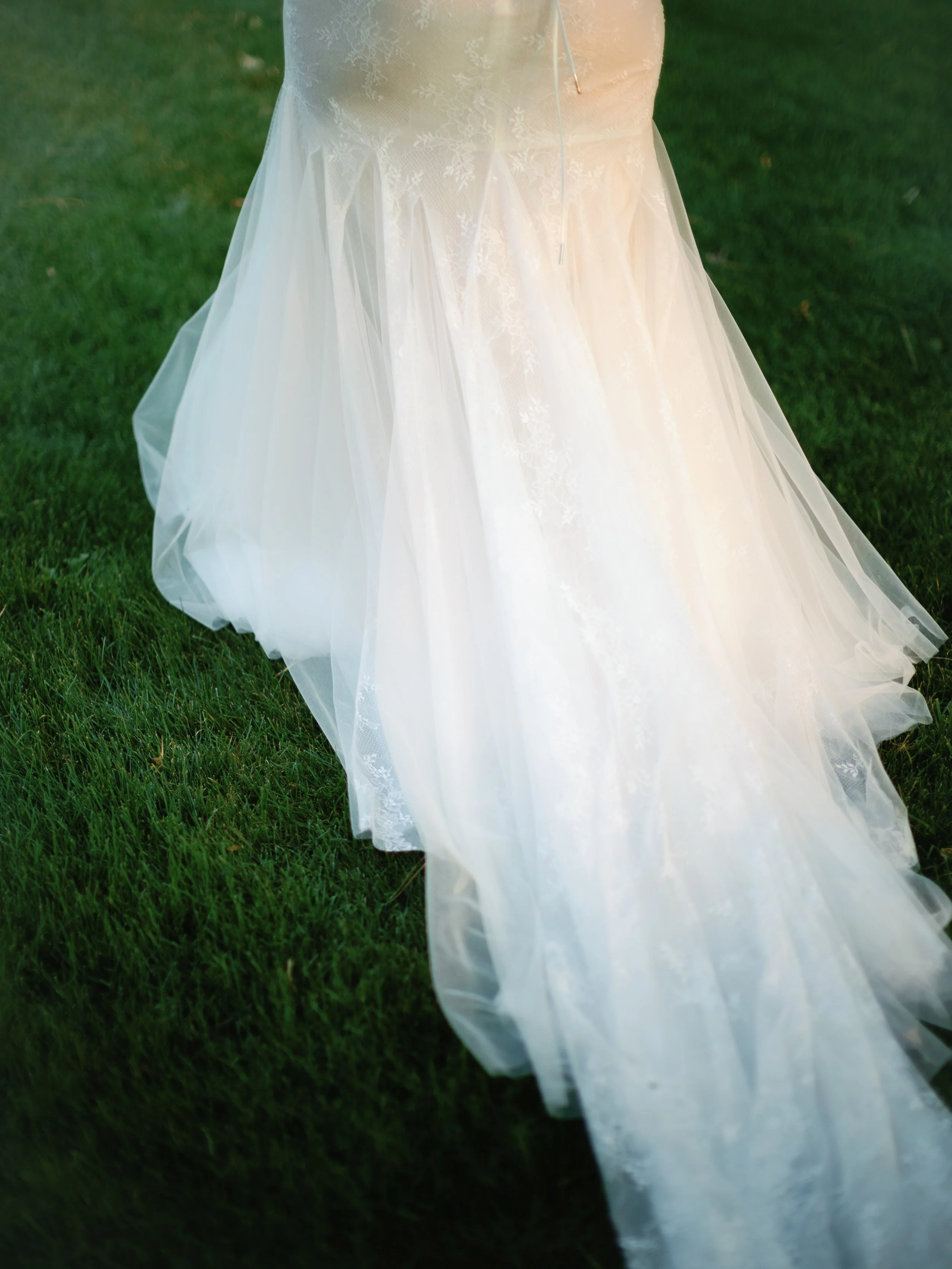 A wedding dress with lace and tulle fabric on grass.