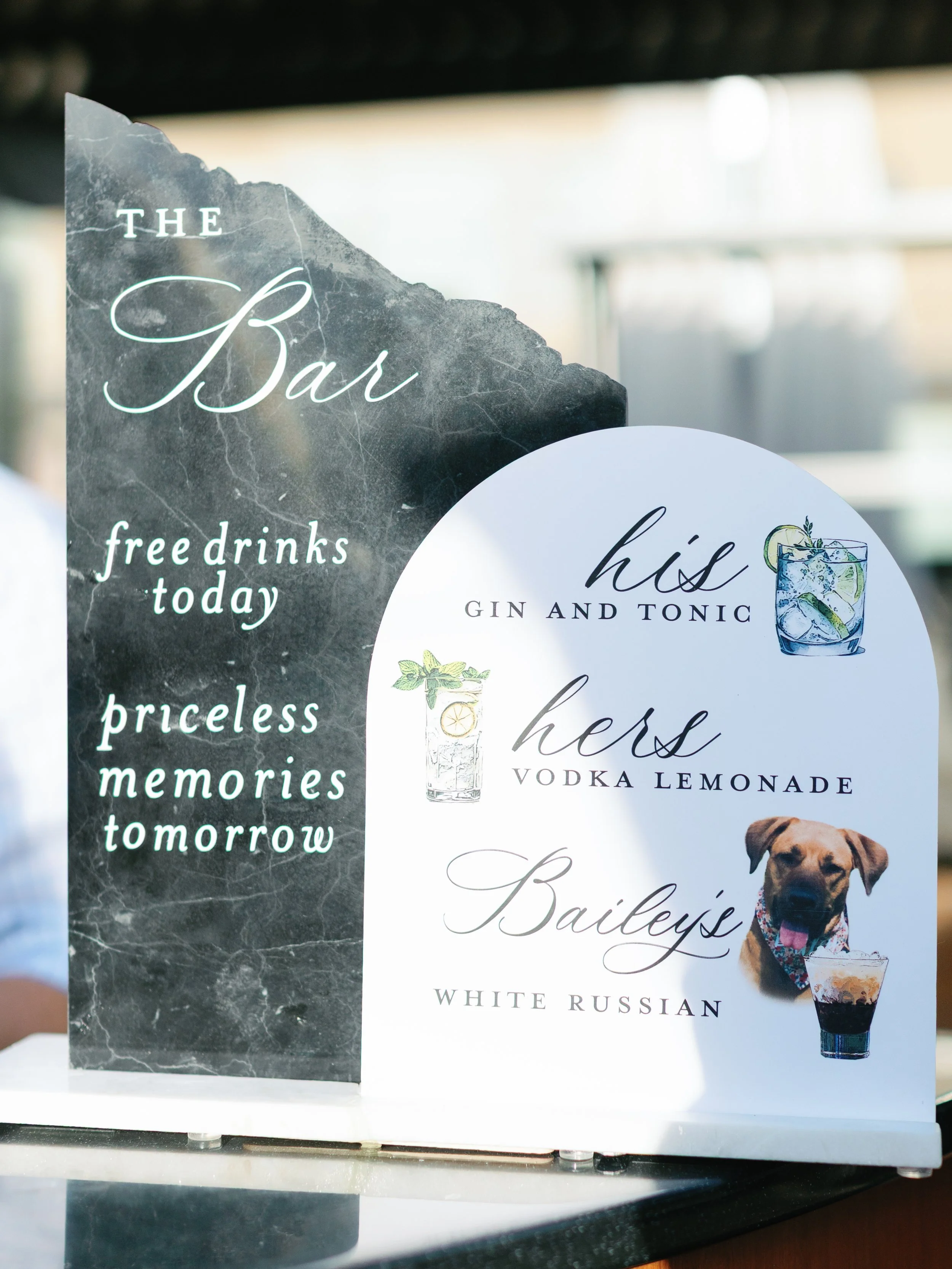 Sign advertising a bar with free drinks today, featuring gin and tonic, vodka lemonade, and White Russian, along with a photo of a dog