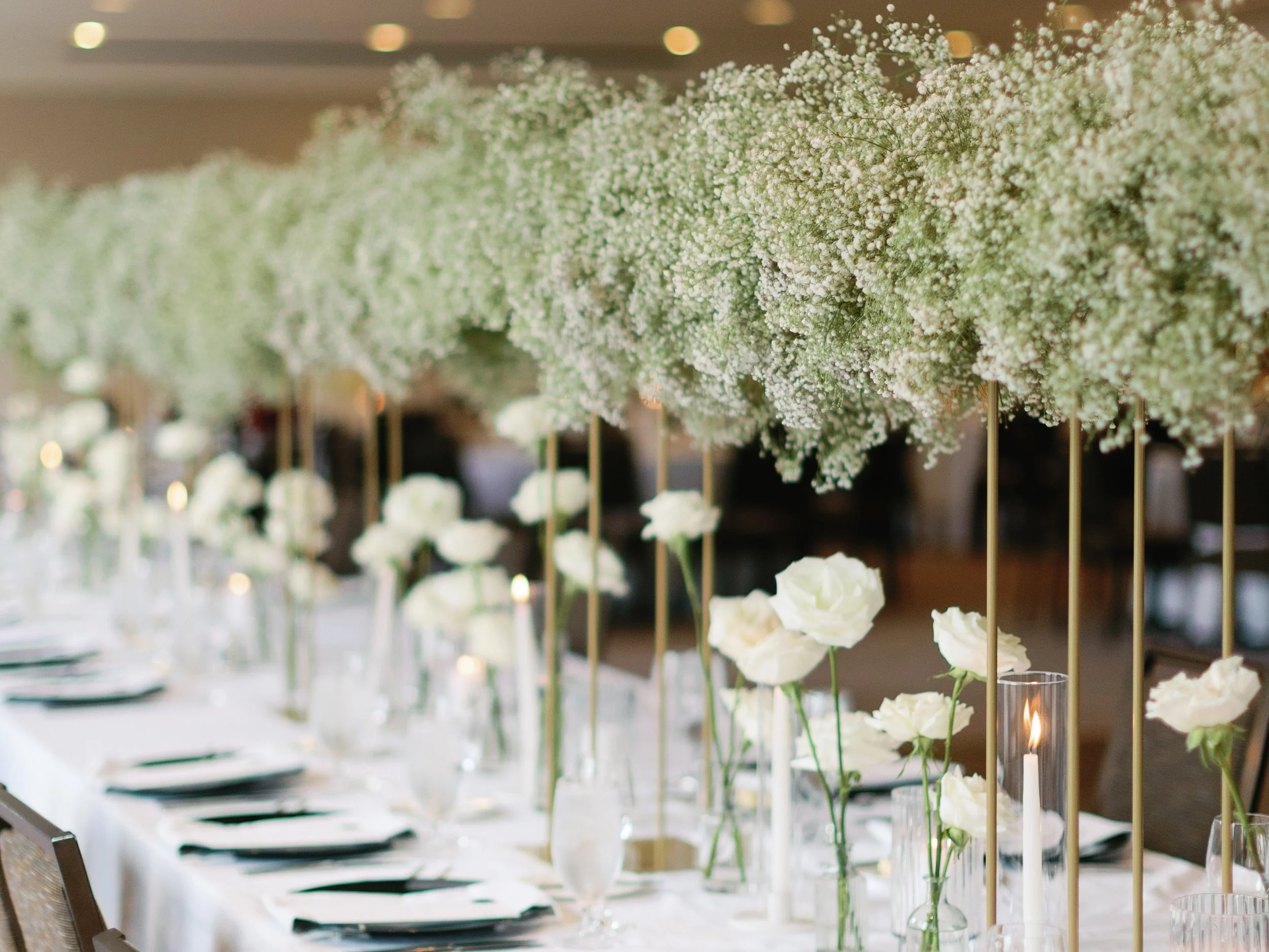 Elegant table setting with white flowers, candles, and tall floral arrangements for a wedding or special event.