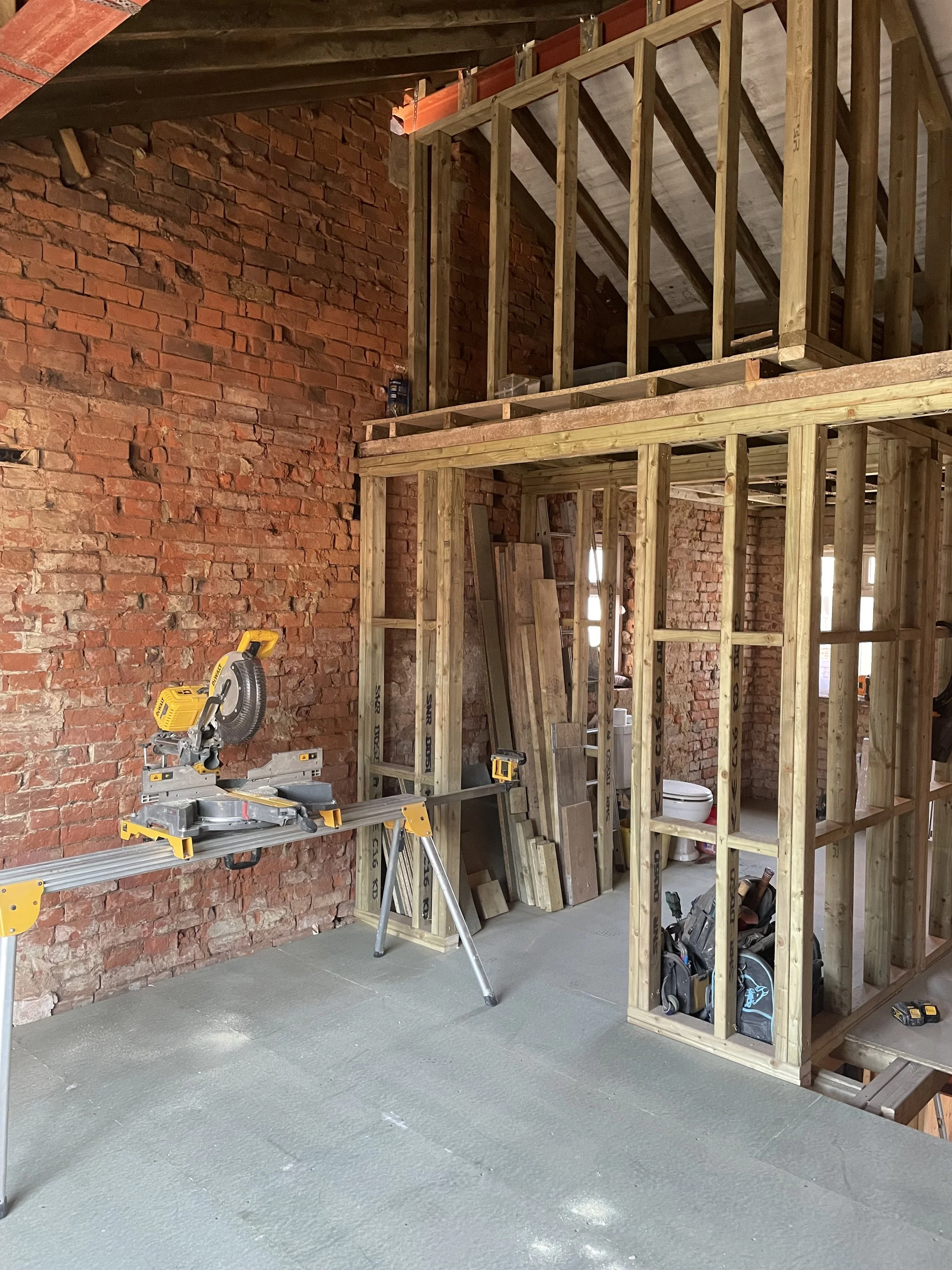 First fix timber studwork forming a walk-in wardrobe and Jack-and-Jill bathroom beneath a vaulted ceiling