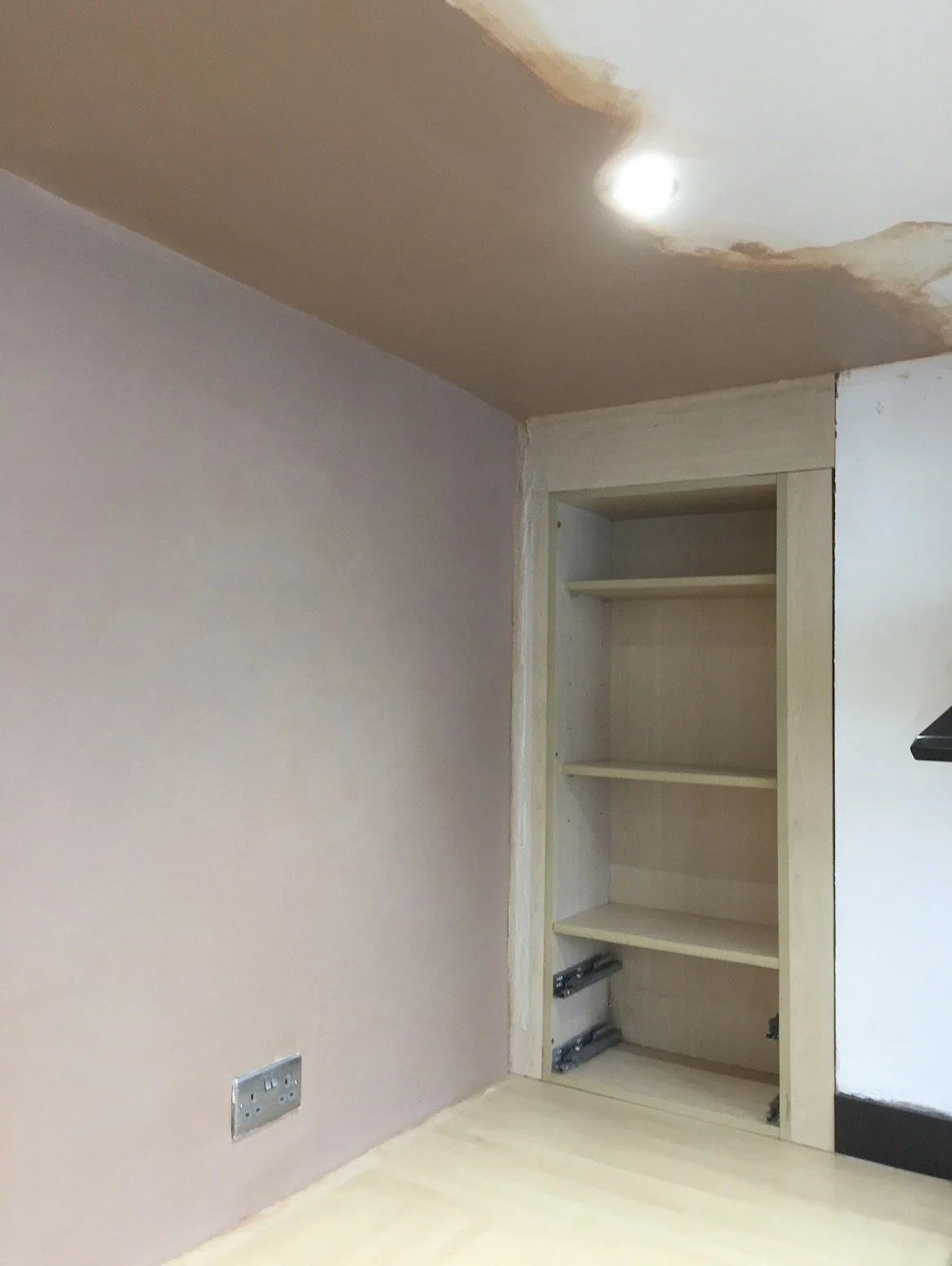 Completed lower-ground-floor wall and ceiling repairs, fully plastered with a smooth finish ready for decoration.