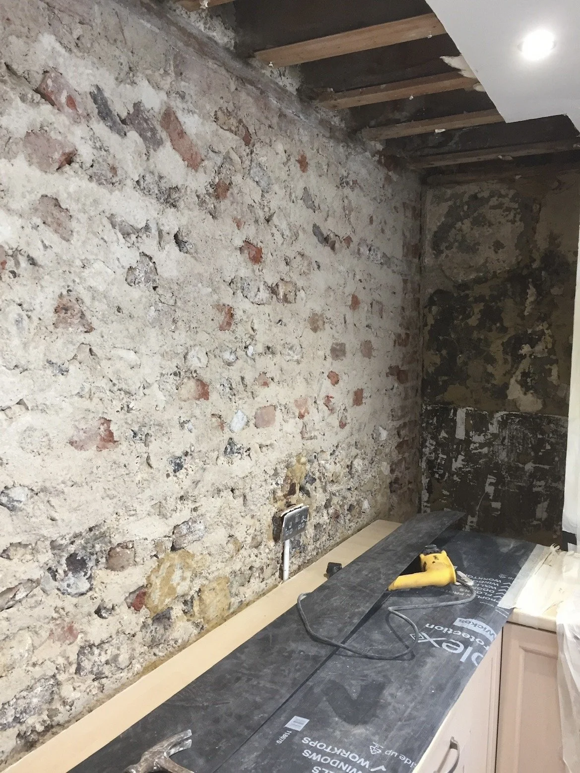 Existing render and damaged finishes removed to expose the original bungaroosh wall construction ready for damp treatment.