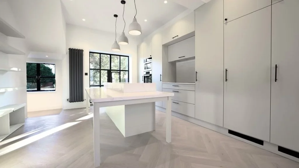 Contemporary kitchen with tall cabinetry, central island, black finishes and Crittall doors opening onto an outdoor terrace