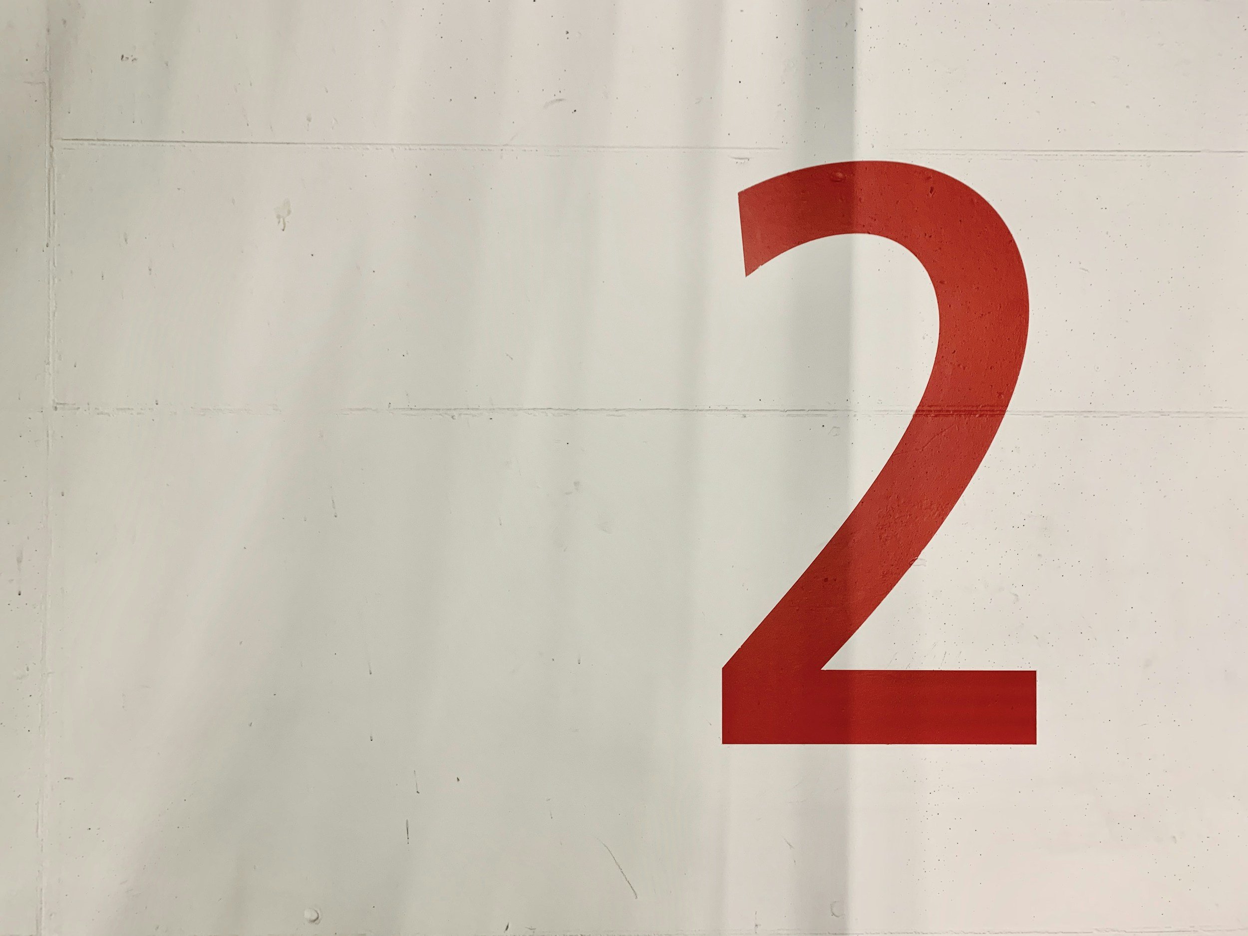 Red number 2 on a white wall.