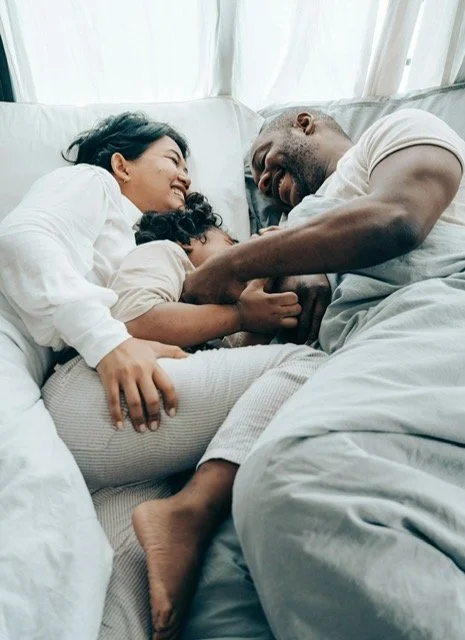 Smiling family of three enjoying time together, illustrating the possibility of moving past family stress and finding connection.