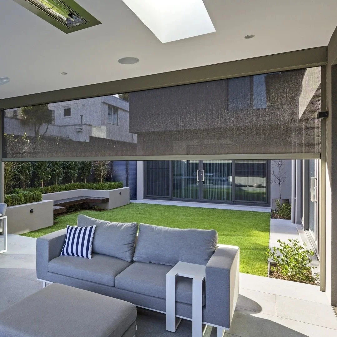 Living room with large patio door leading to a backyard with green grass, small trees, and modern outdoor furniture.