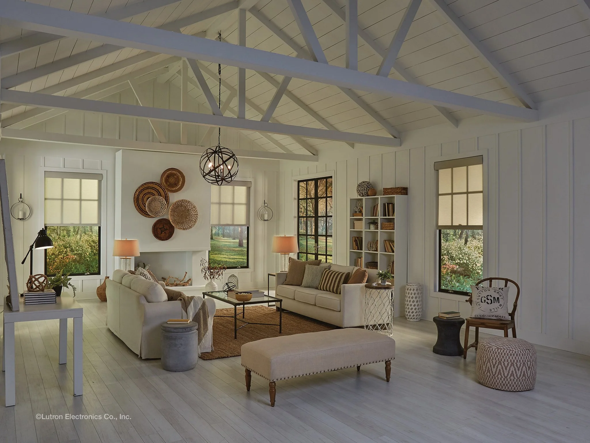 Motorized fabric roller shades installed on tall windows in a bright modern living room with vaulted ceilings, providing soft natural light, privacy, and smart home window treatment design.