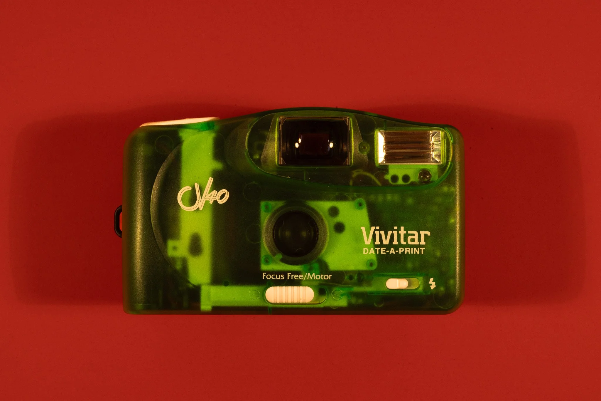 Top view of a green Viviatar Vivitar 35mm film camera on red background.