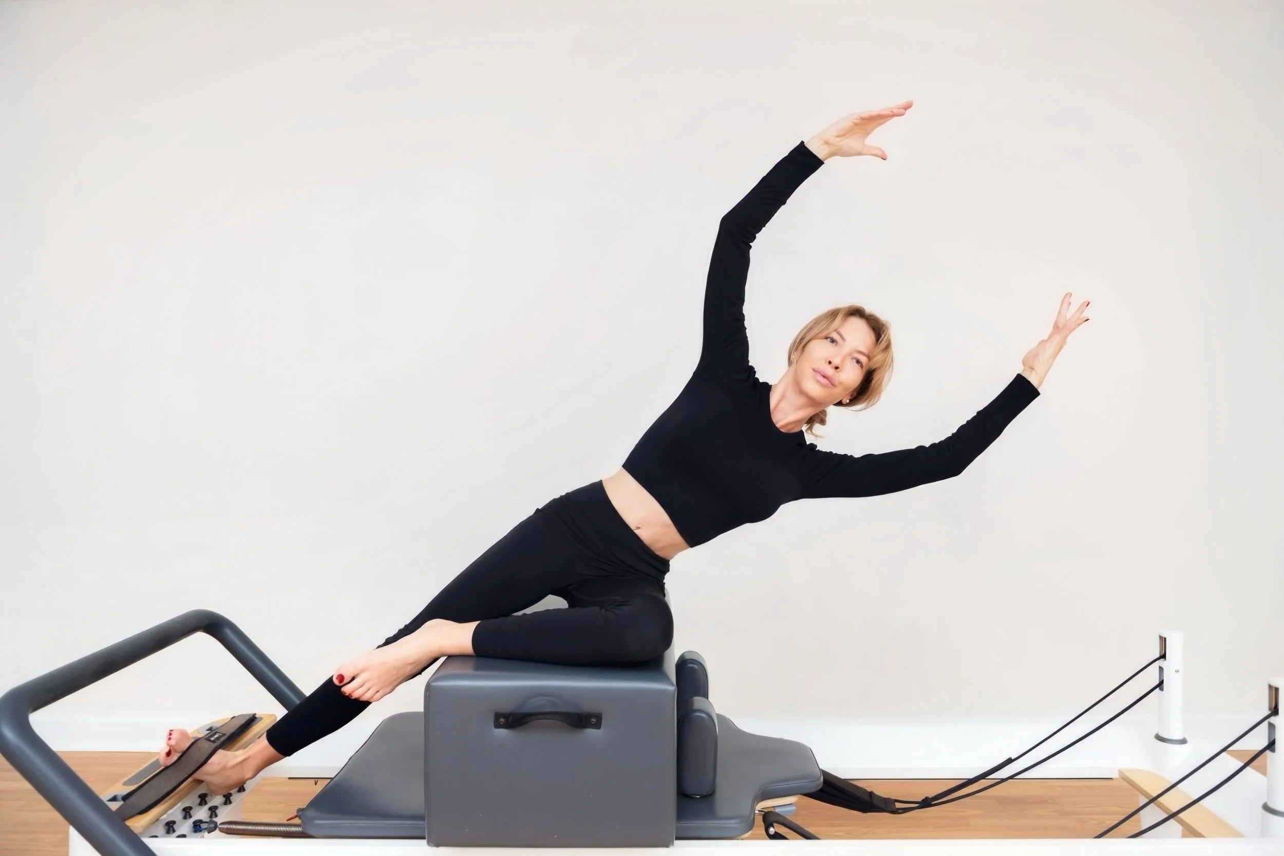 Kathryn Stoneman, a female pilates instructor based in Nassau, Bahamas;  doing mermaid on the short box on a Balanced Body pilates reformer machine.