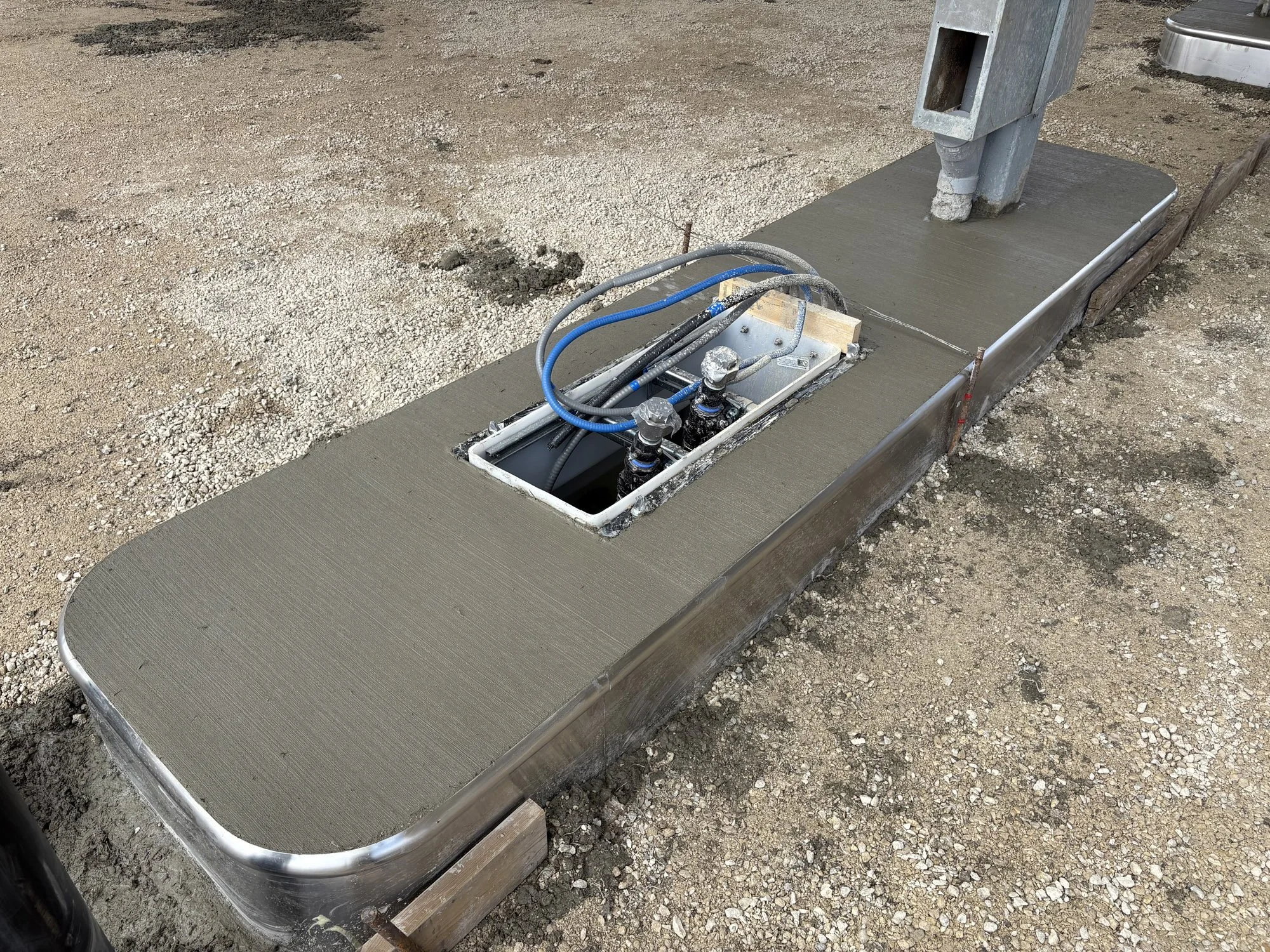 Concrete foundation with plumbing and electrical boxes installed for an outdoor structure.