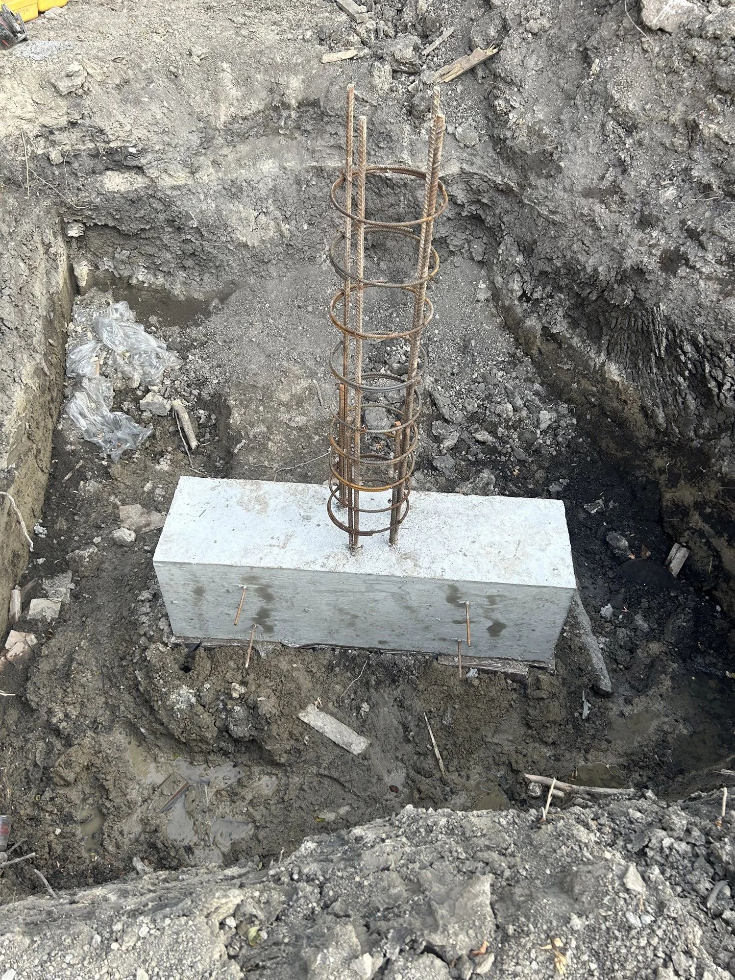 Reinforced concrete foundation with exposed rebar in a construction site.