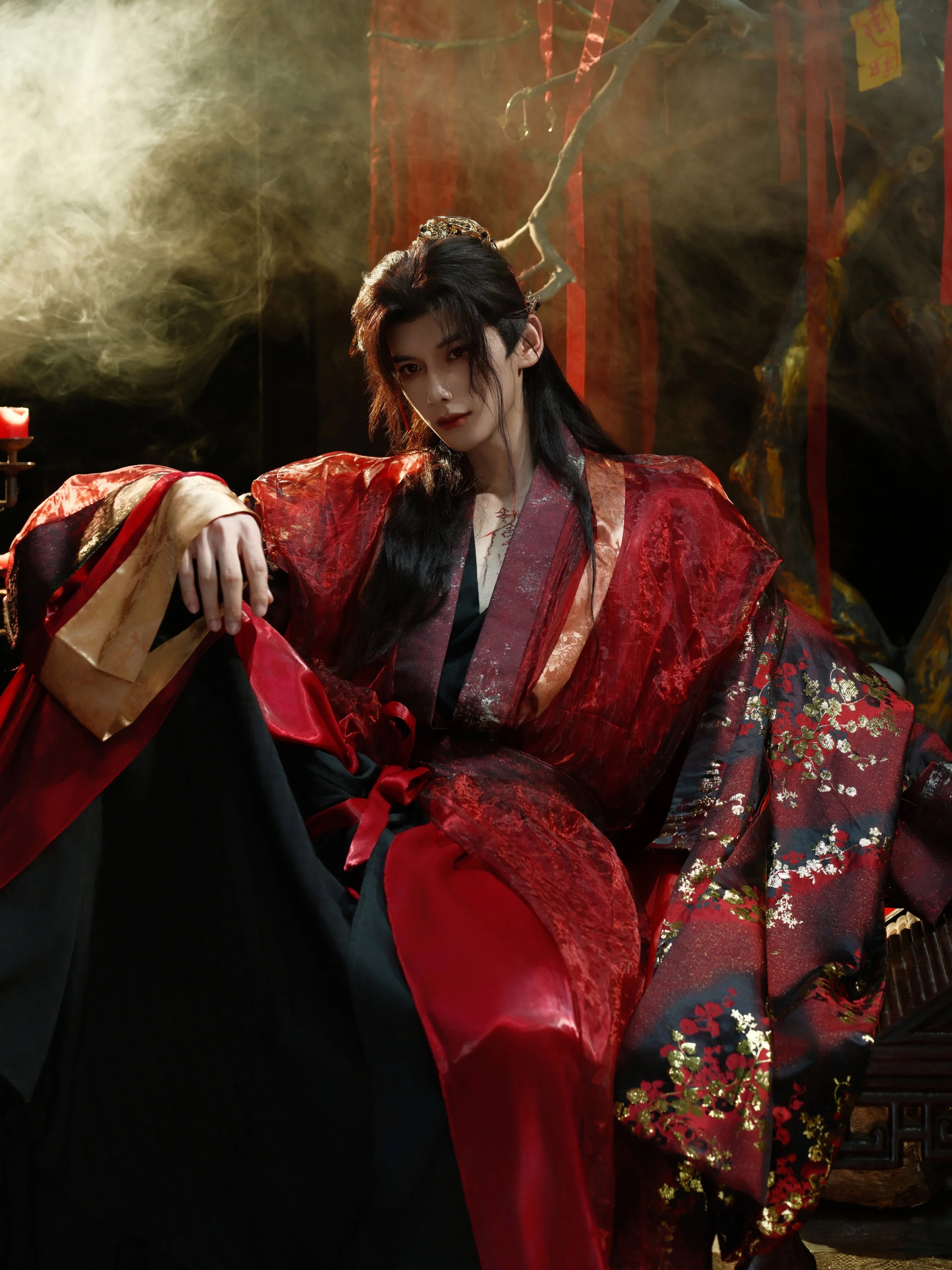 Person dressed in traditional Chinese costume in a dark, smoky setting with red and gold decorative elements.
