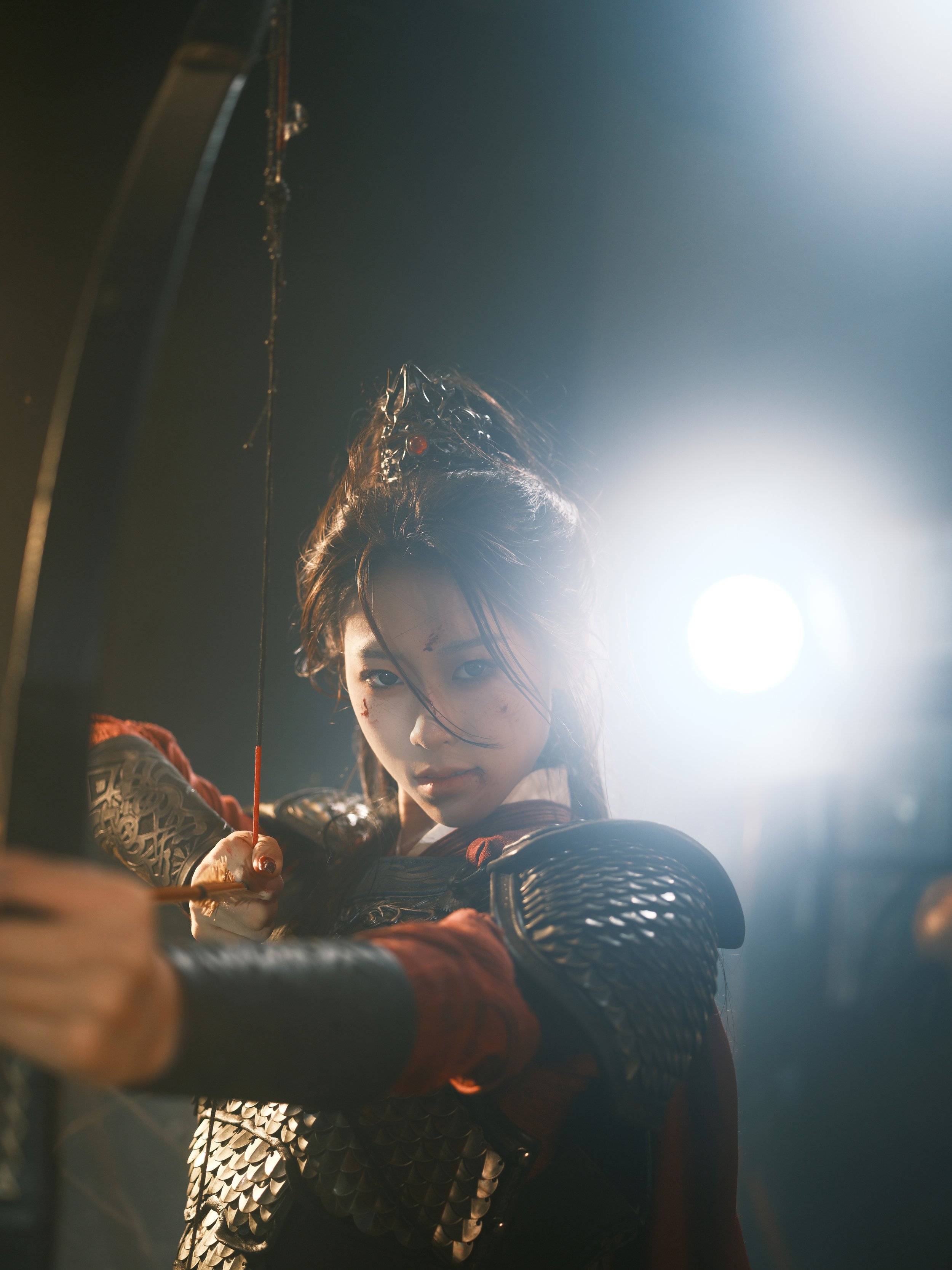 A female warrior dressed in armor in an action pose, aiming a bow and arrow, with dramatic lighting highlighting her determined expression.