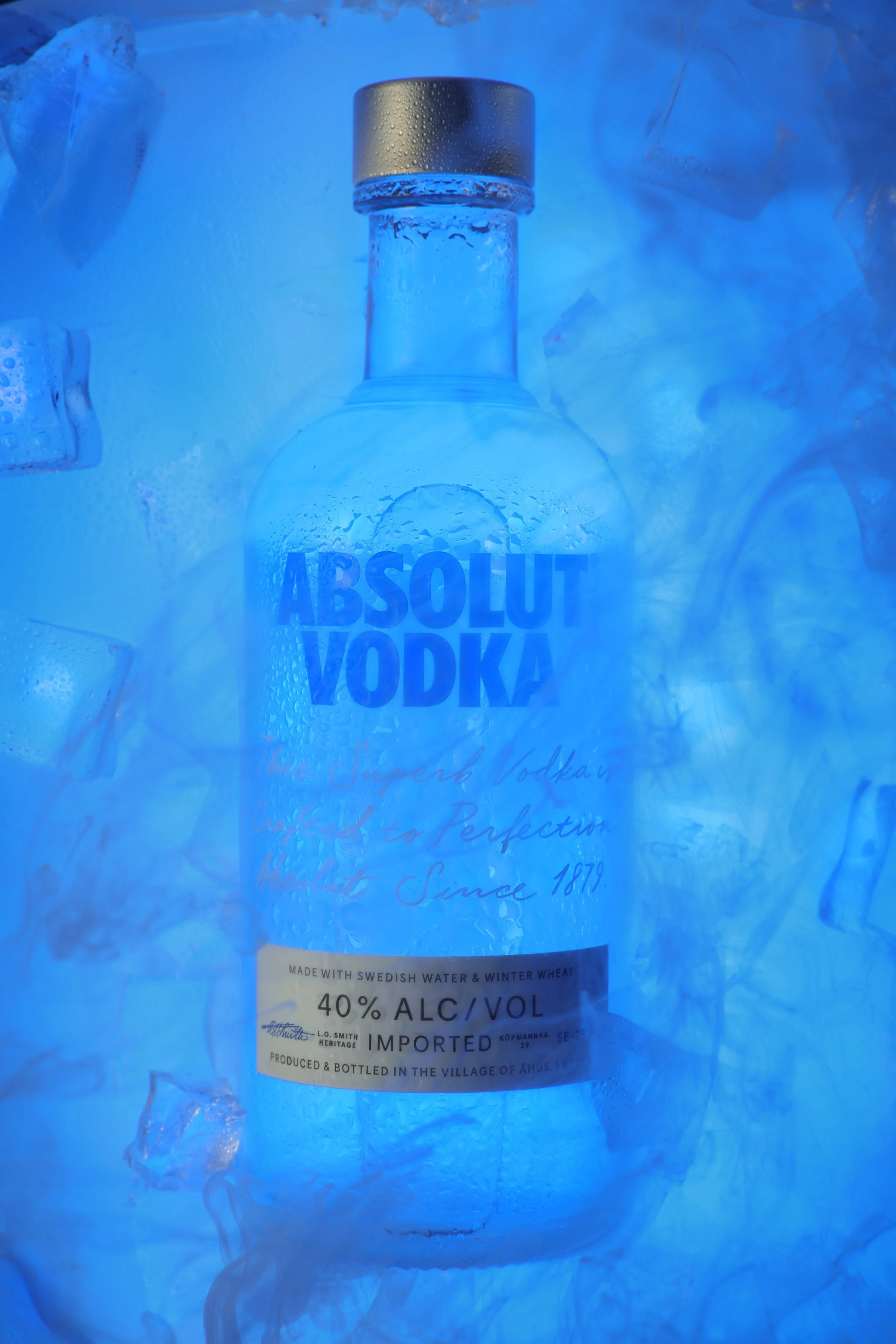 A bottle of Absolut Vodka surrounded by ice and fog, with a blue lighting effect.