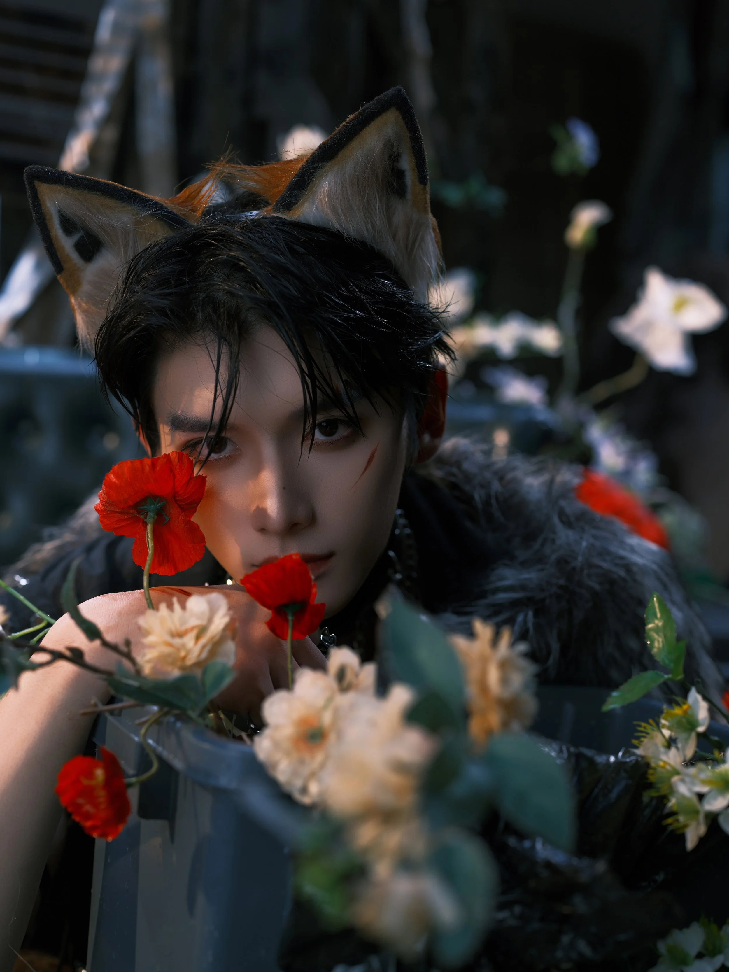 Person with black hair wearing animal ears and a fur garment surrounded by red and white flowers.