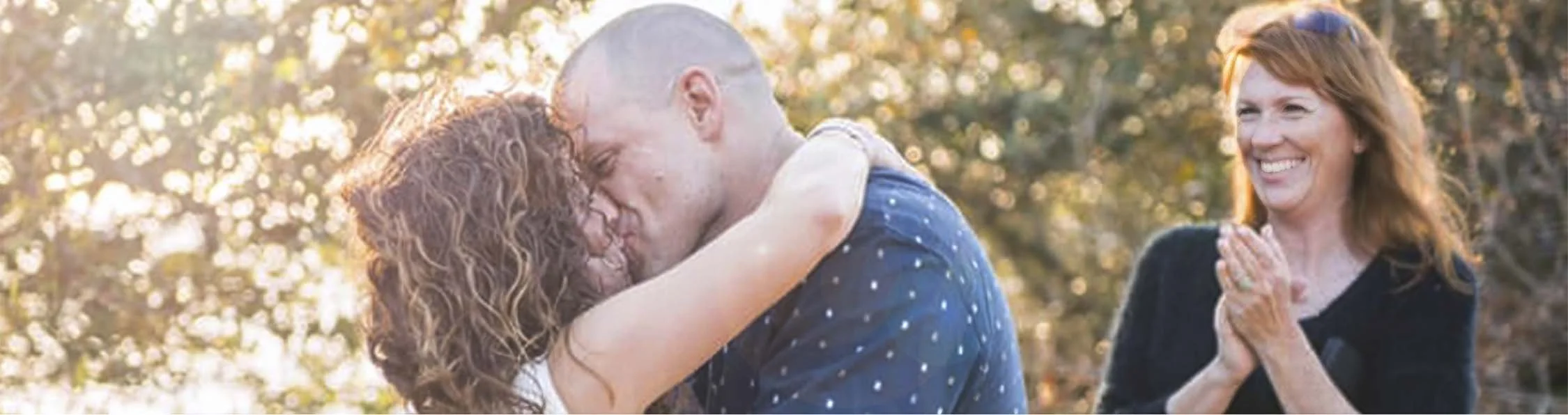 A bride and groom kiss as Rev Melody McBride smiles and claps. Outer banks OBX wedding officiant.