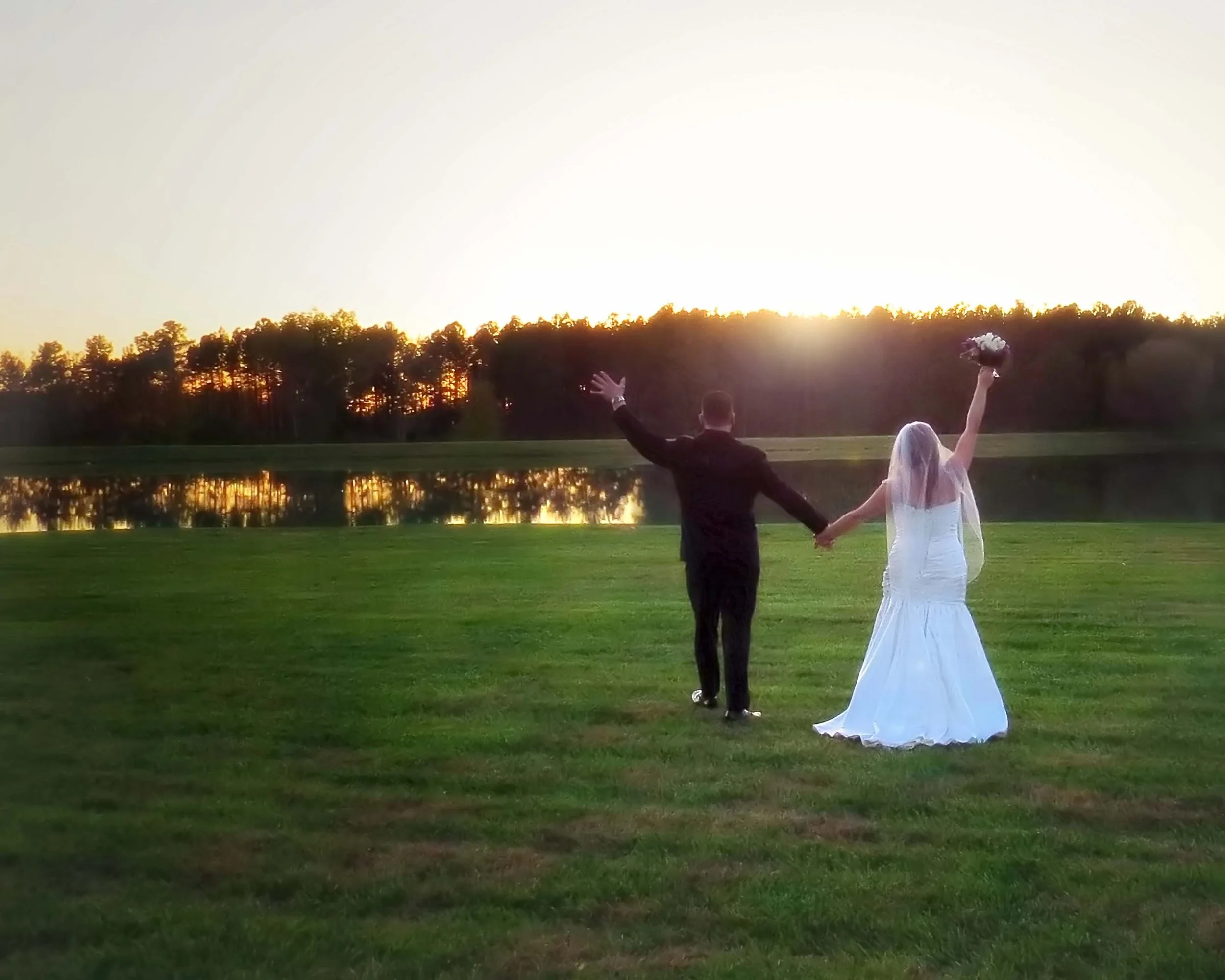 Bride and groom walk hand in hand into an Outer Banks sunset together.