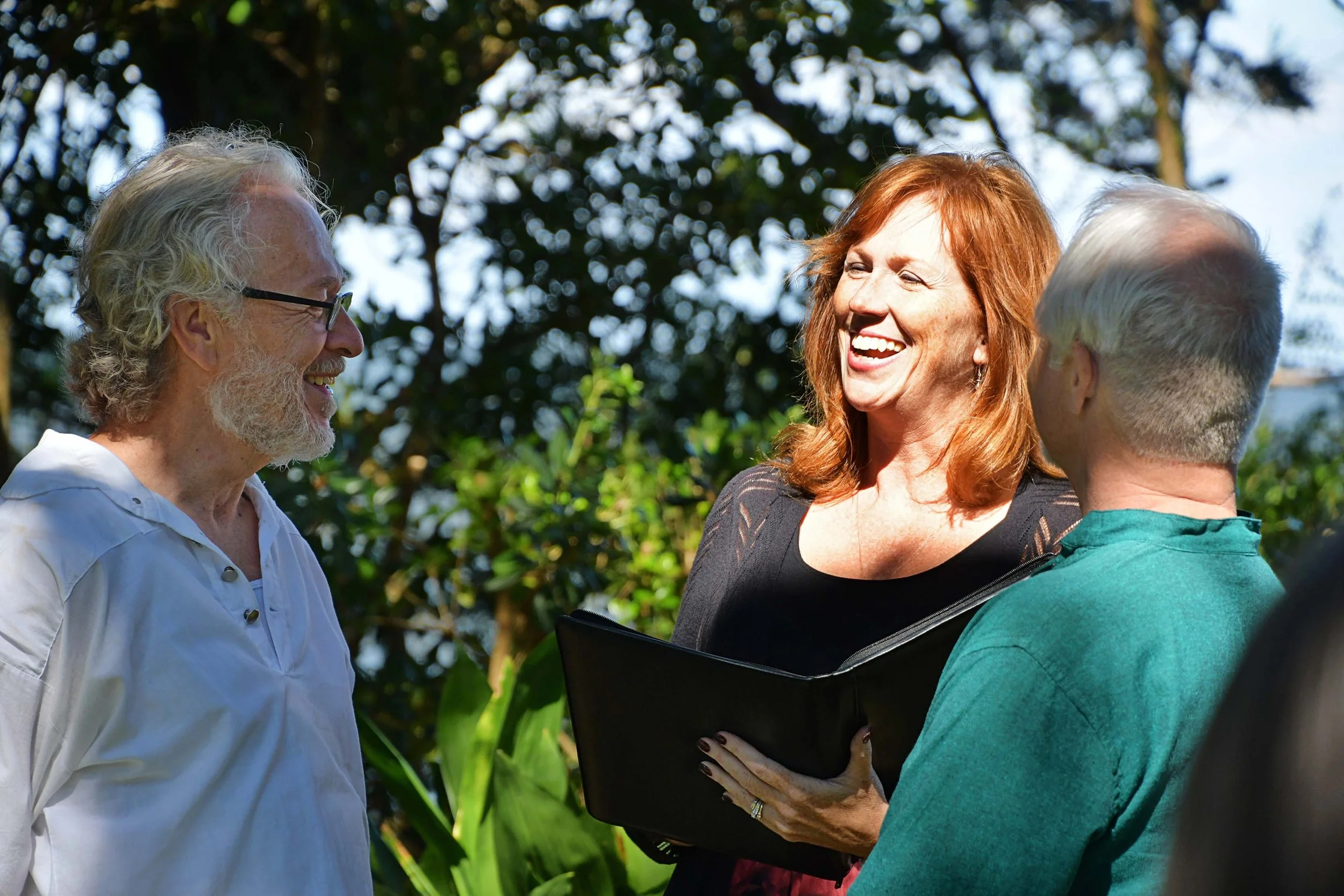 Two men getting married and Outer Banks wedding officiant laughing during wedding ceremony.