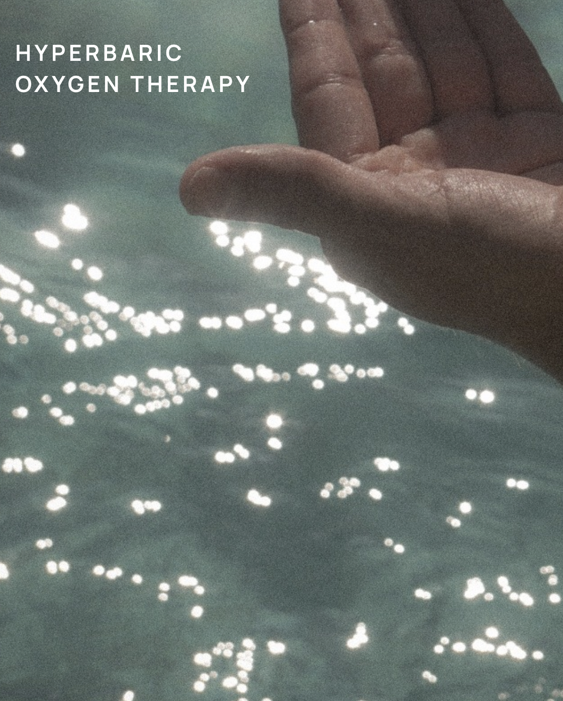 A hand with fingers close together is held above shimmering water, with sunlight reflecting off the surface creating sparkling light effects. The text 'Hyperbaric Oxygen Therapy' is in the upper left corner.