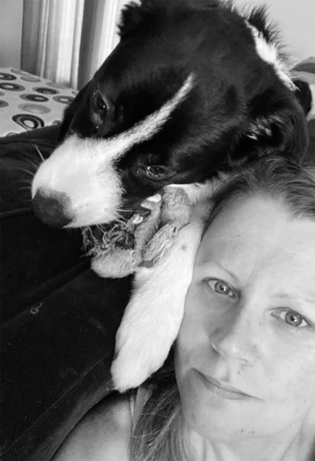 Dog Trainer Horshem. A black and white photo of a woman with long hair and a puppy. The puppy, with black and white fur, and the woman's face is close to the camera with a slight smile.