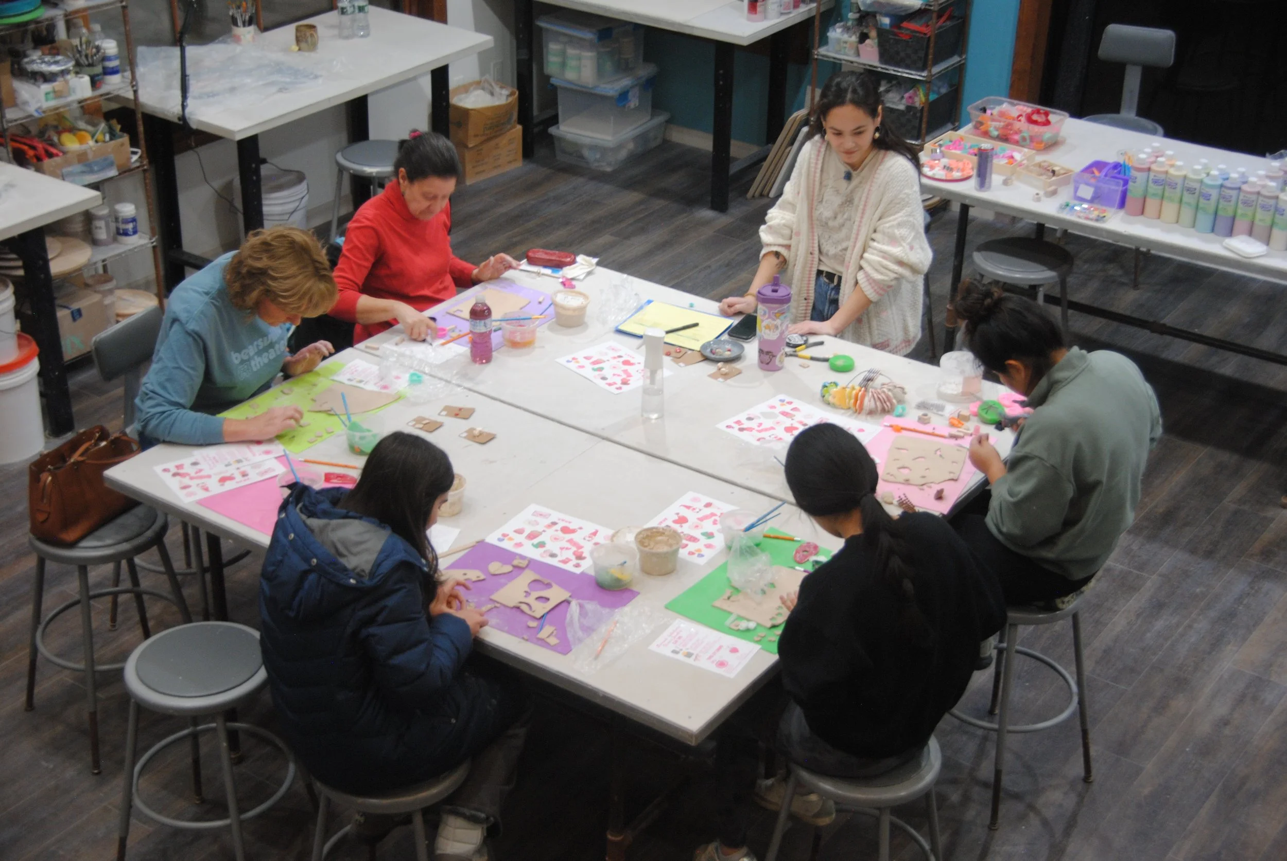 People sitting around a table engaging in arts and crafts activities, with supplies like colored paper, scissors, and glue on the table.