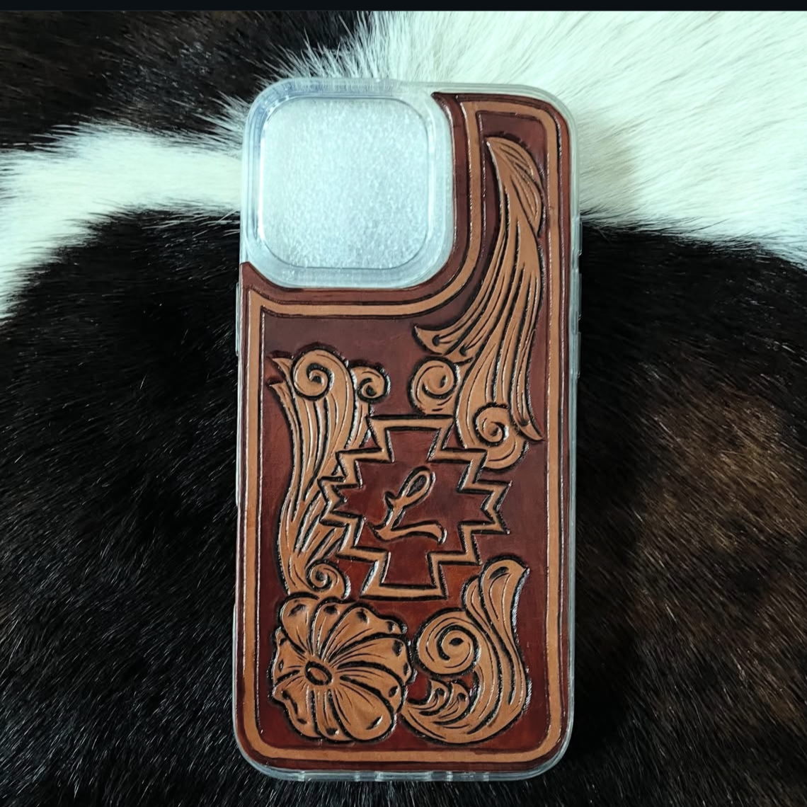 Smartphone with a decorative, floral, and geometric design case, resting on black and white animal fur.