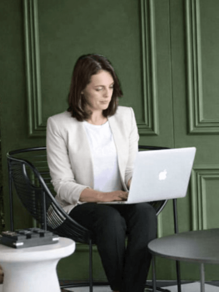 Rowena Doyle working on a laptop in a calm, modern workspace.
