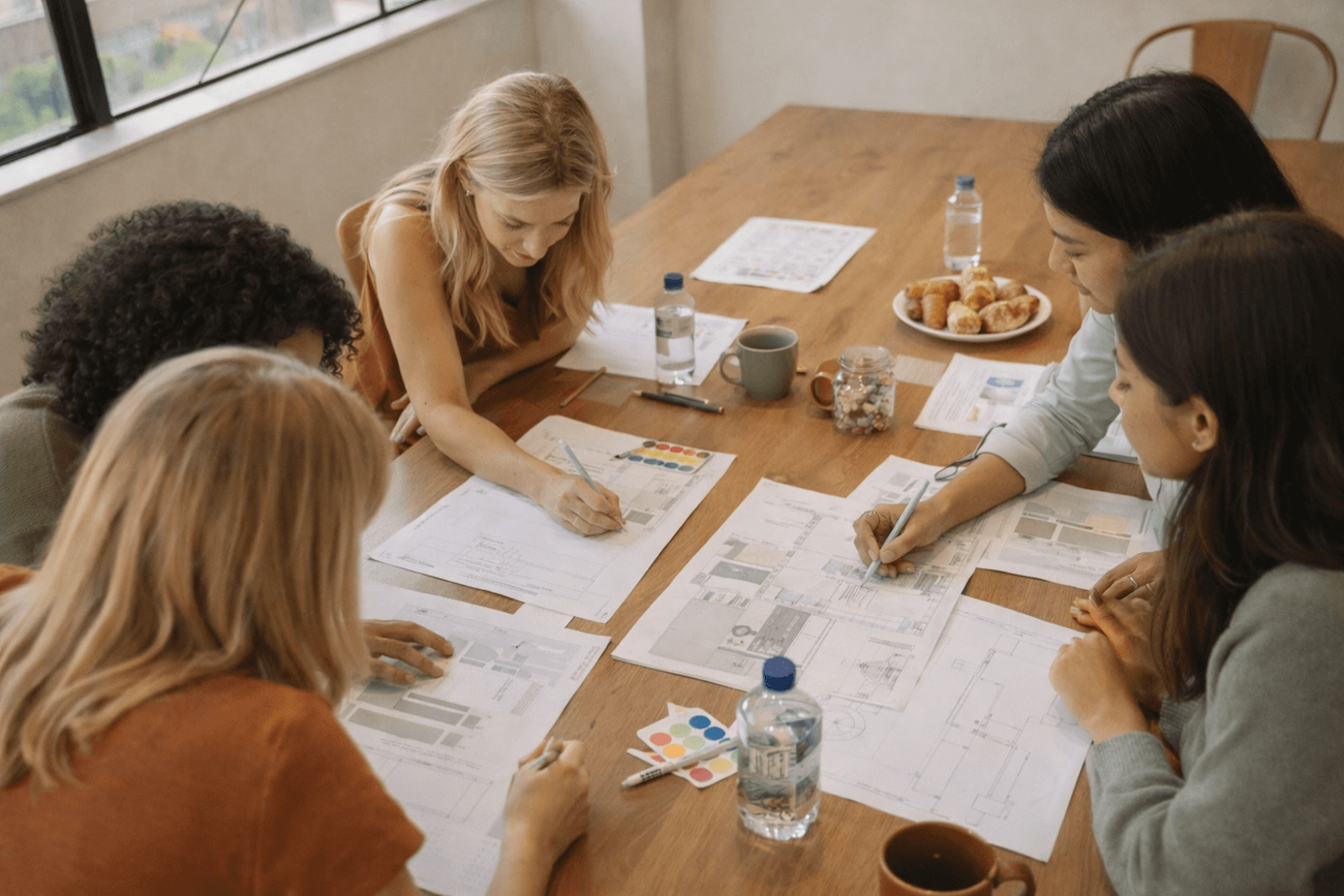 Team collaborating around a table with strategy documents and notes.
