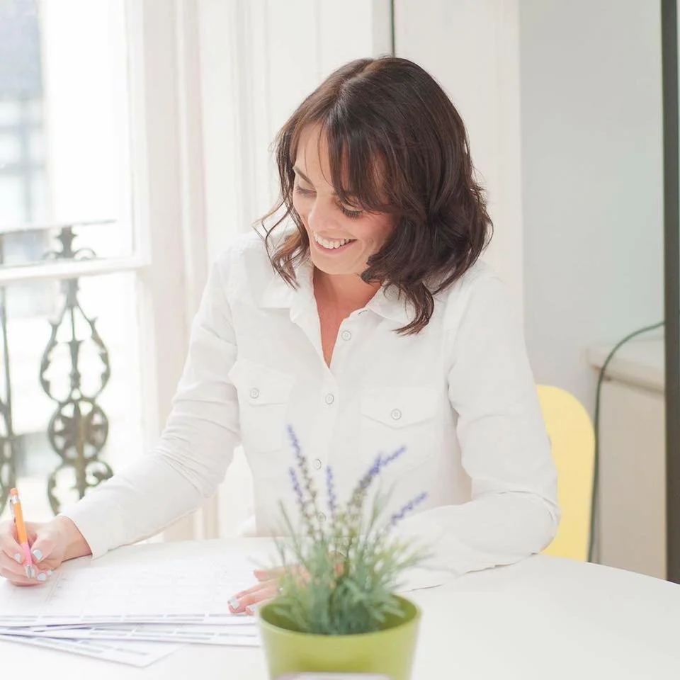 Rowena Doyle writing notes at her desk in a bright office.